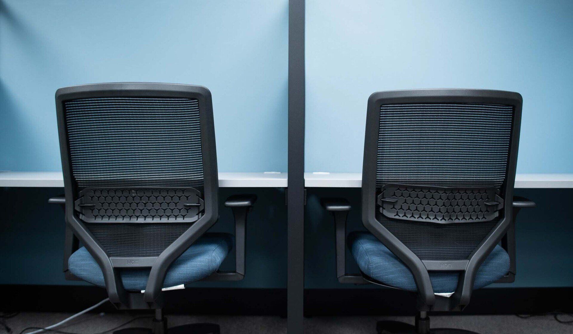 two office chairs are sitting next to each other in light blue cubicles