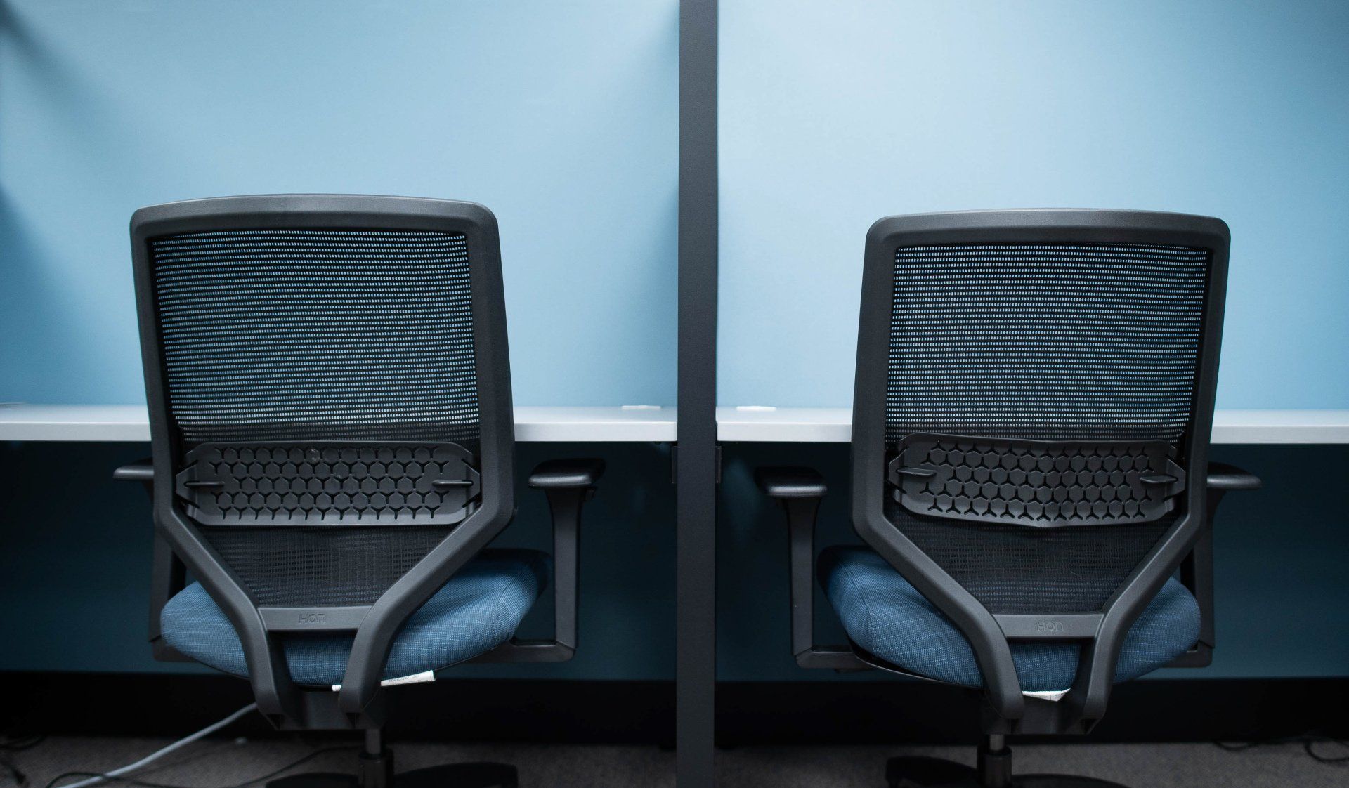 Two office chairs are sitting next to each other in a cubicle.