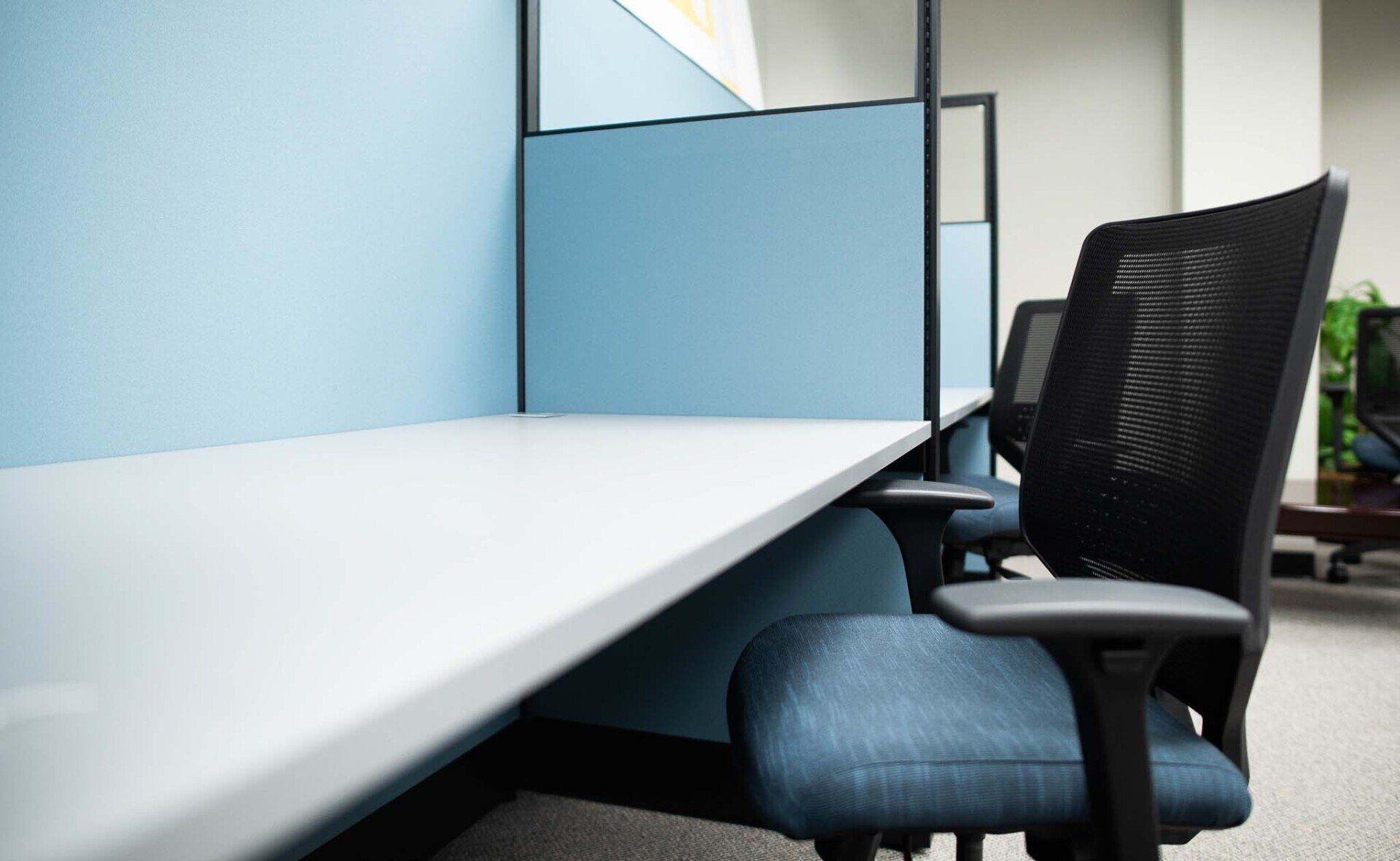a cubicle with a blue wall and a black chair