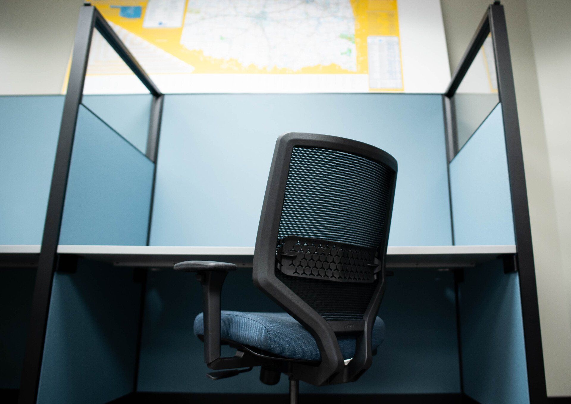 A cubicle with a chair and a map on the wall