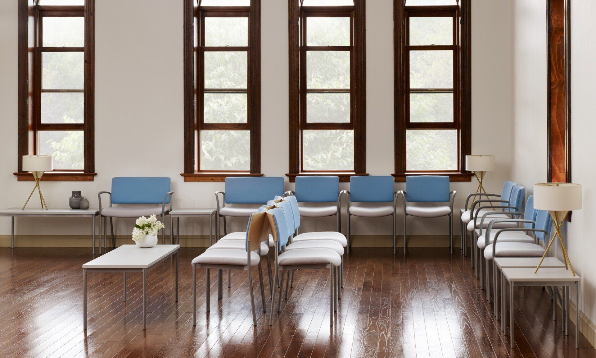 a waiting room with blue chairs and white tables