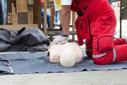 A Man is Kneeling Down and Giving a Heart Massage to a Mannequin — Revive Training in Tweed Heads, NSW