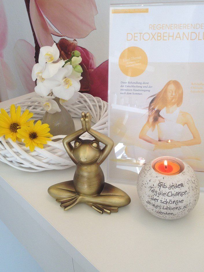 Eine Froschfigur sitzt auf einem Tisch neben einer Kerze