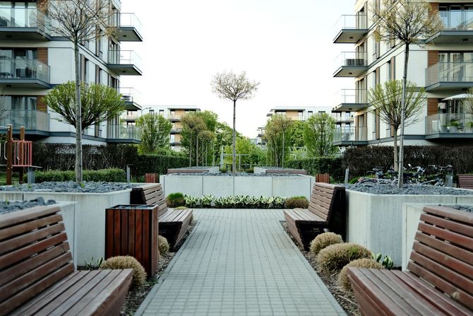 Modern apartment courtyard with benches, planters, and a paved central walkway