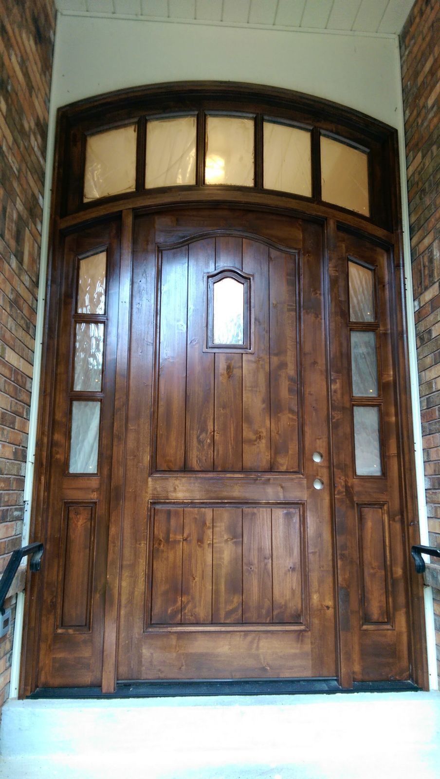 A large wooden door with a brick wall behind it.