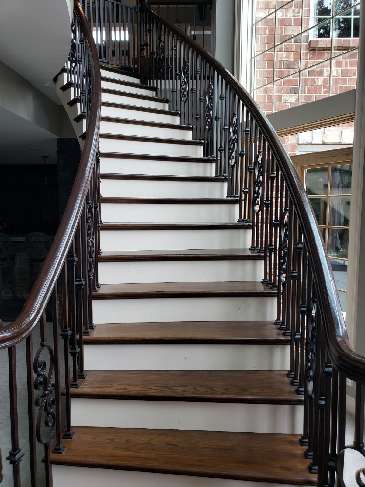 A curved staircase with white steps and a wrought iron railing