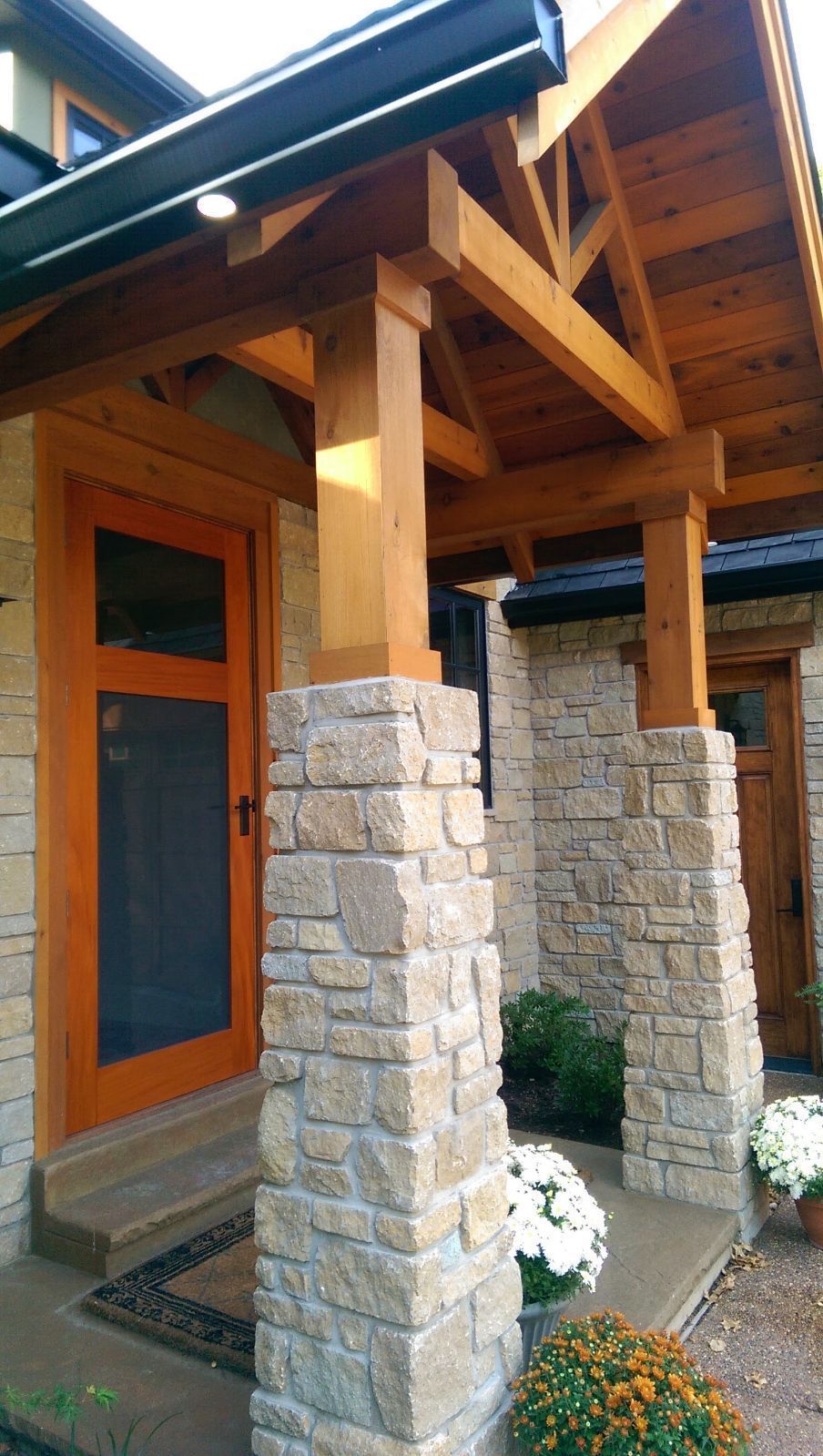 A stone house with a wooden porch and a screen door.