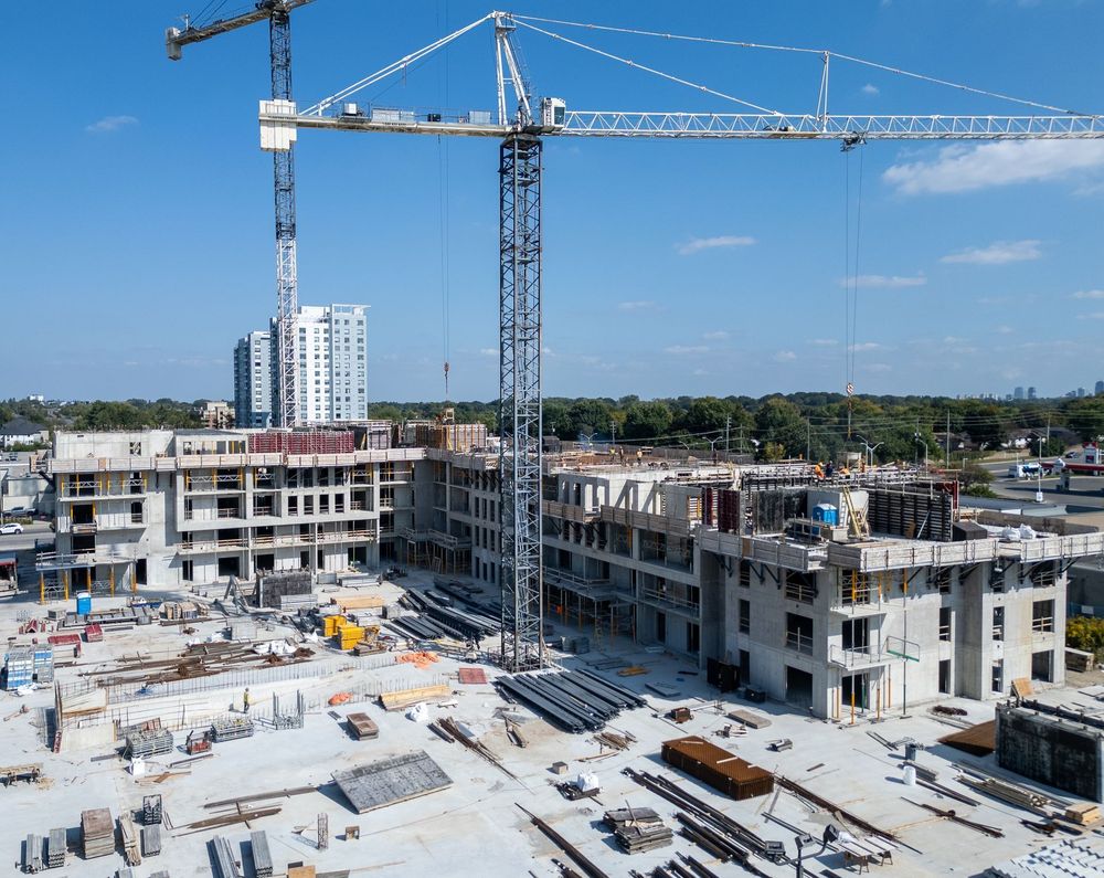 Construction site with cranes and unfinished concrete buildings under a clear blue sky