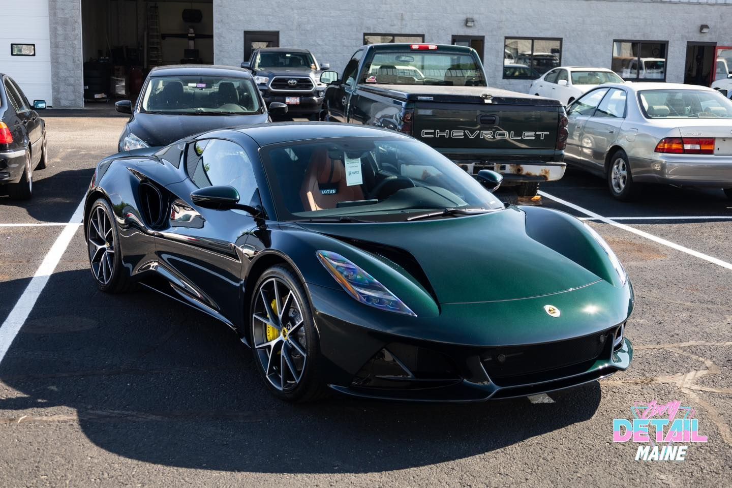 Green Lotus sports car parked in a lot, surrounded by other vehicles.