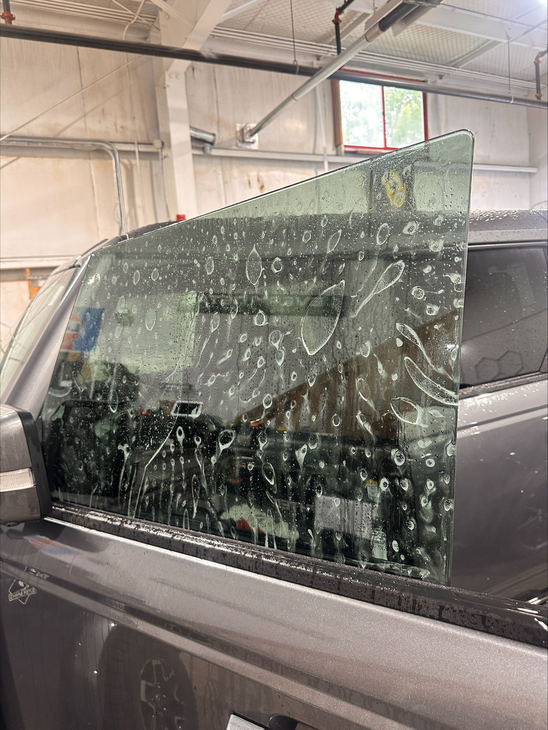 A car with a broken window is parked in a garage.