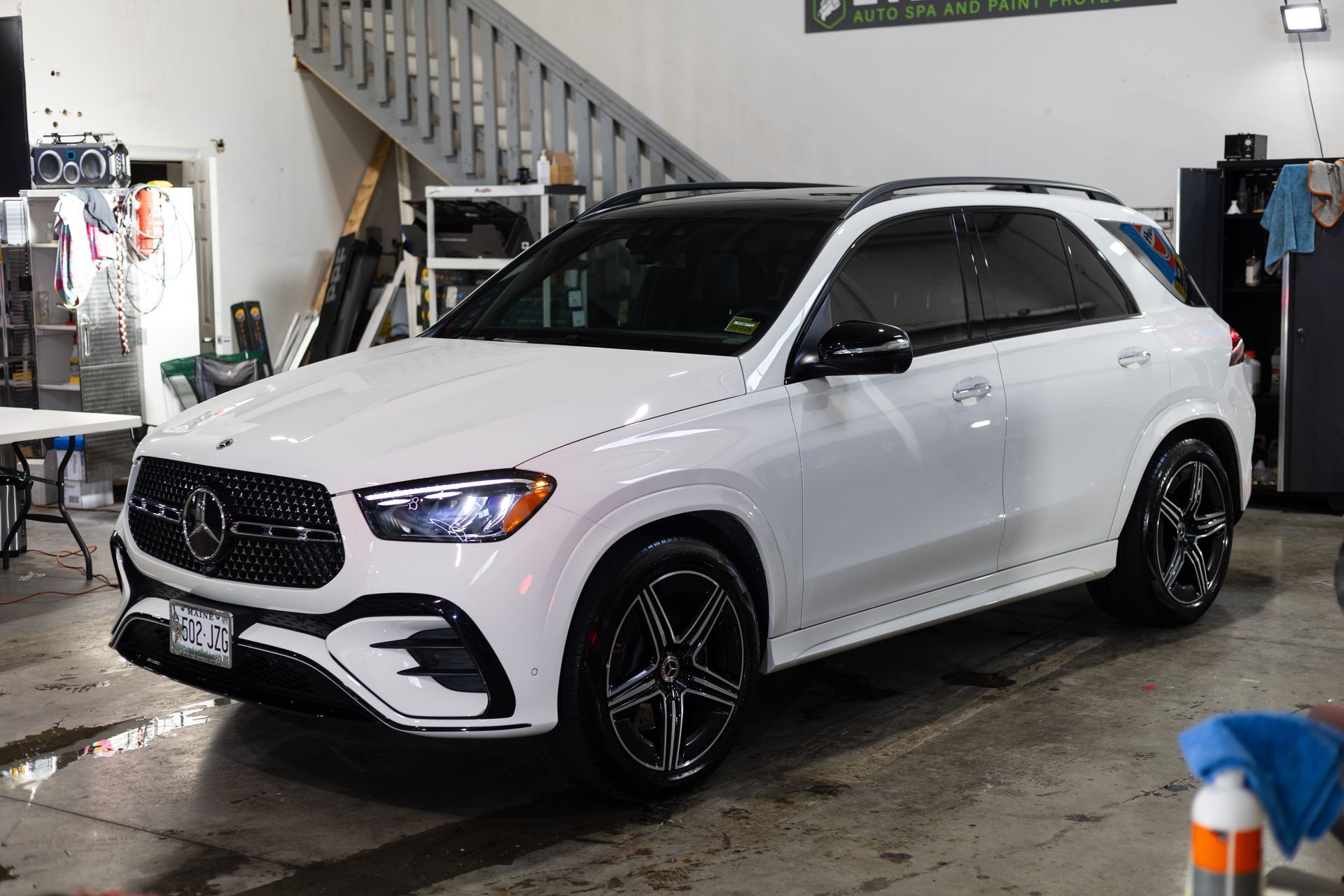 White Mercedes-Benz GLE SUV parked inside a garage, with tinted windows and black wheels.