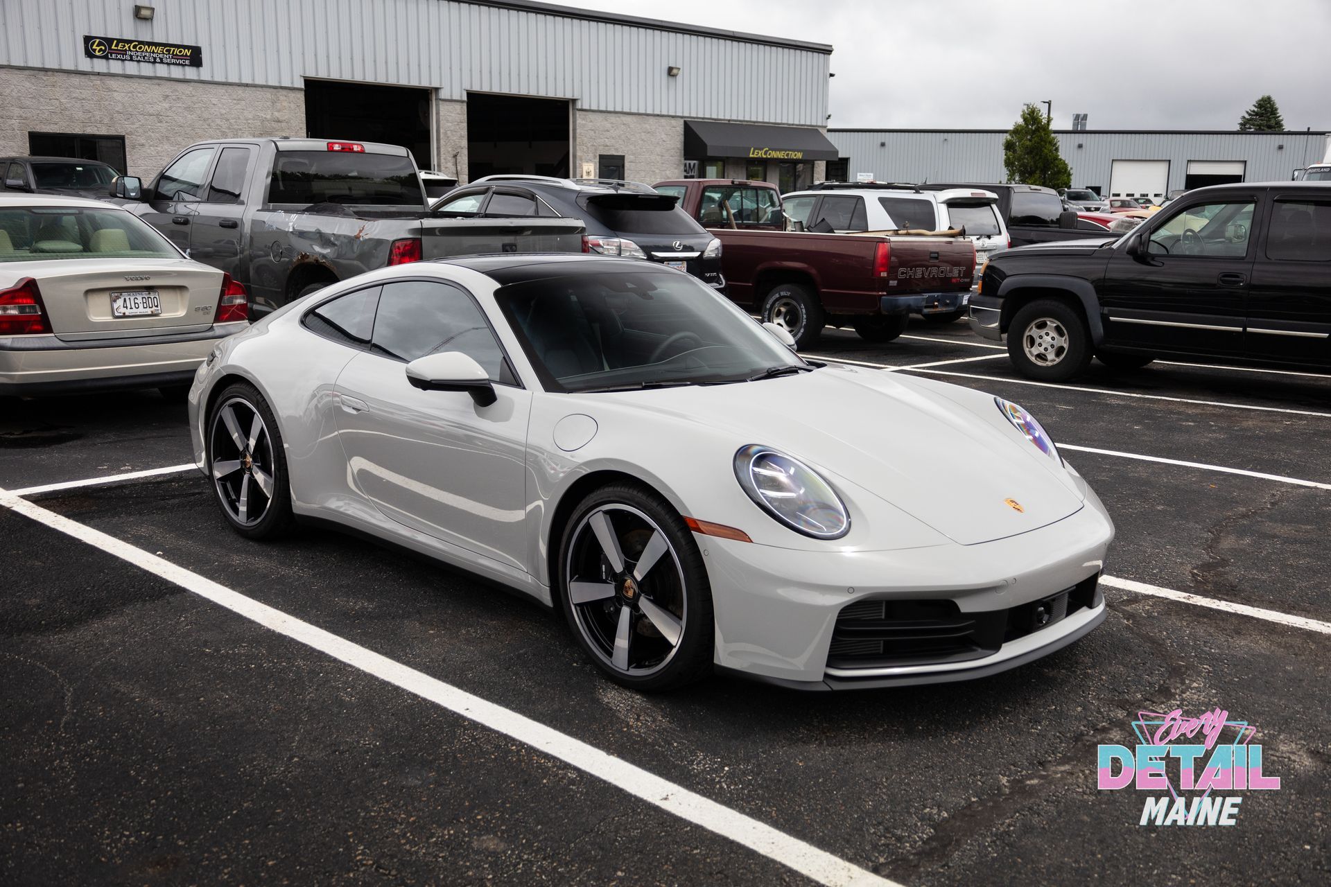 White Lamborghini hood with gold emblem, parked next to black car.