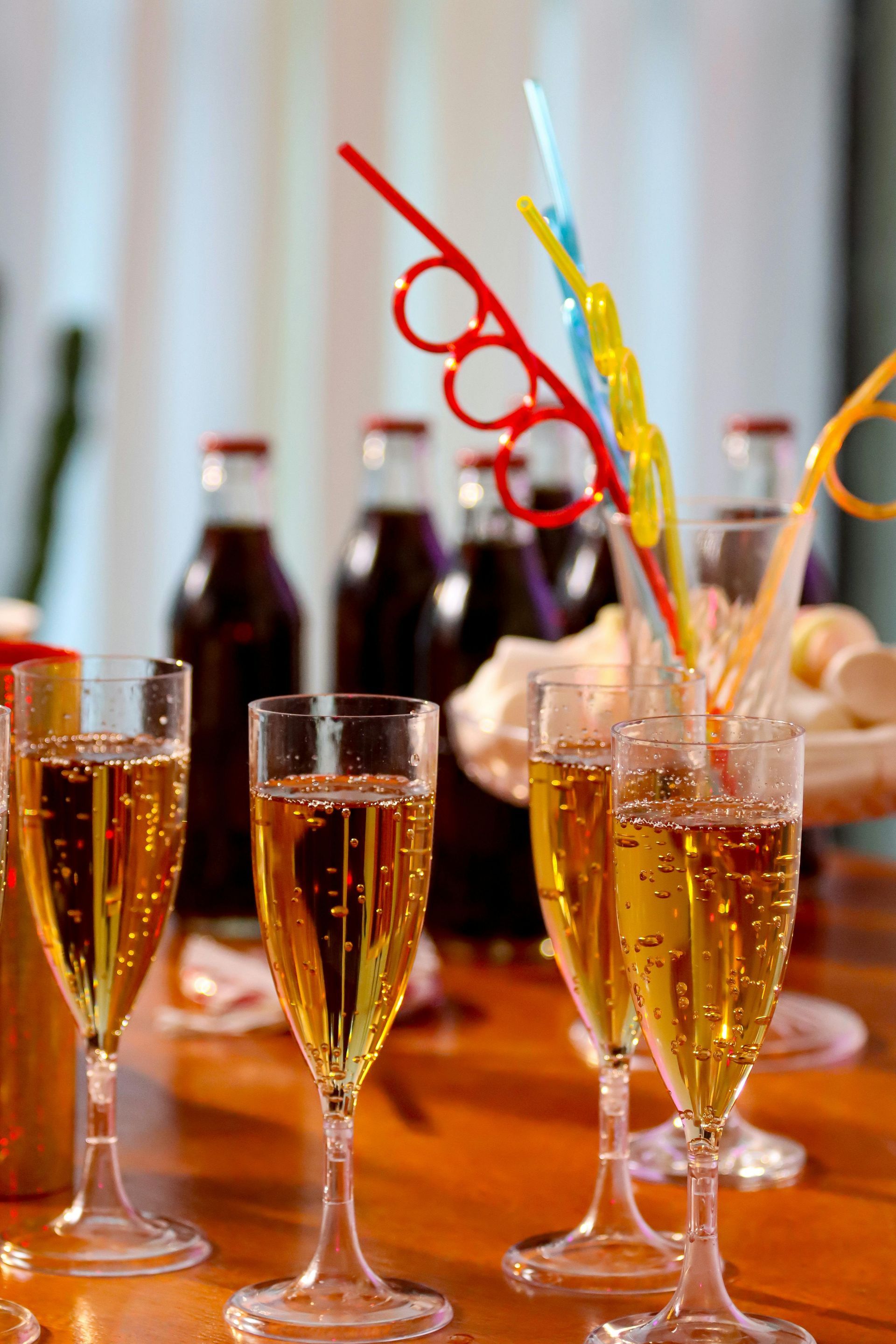 A row of champagne glasses with colorful straws on a table