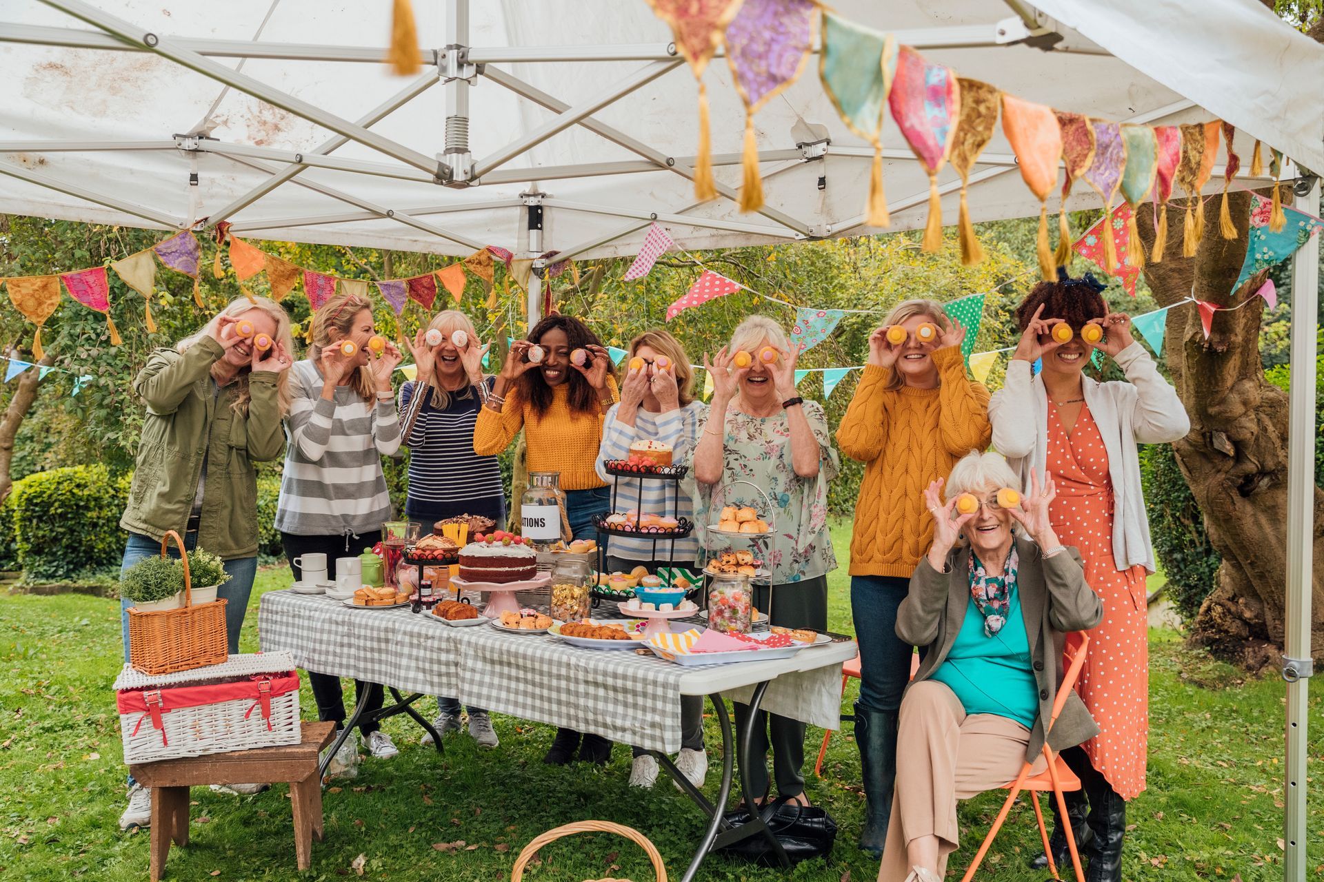 A group of people are standing around a table with food.