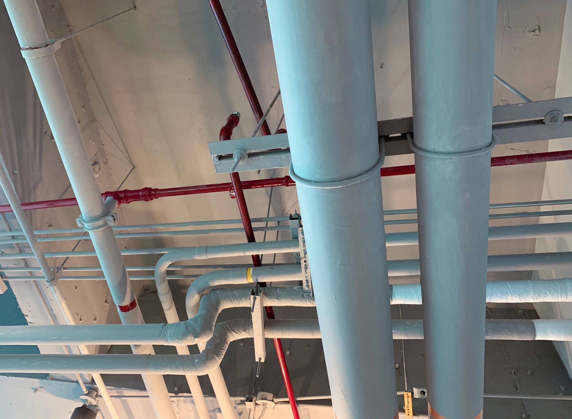 A bunch of pipes are hanging from the ceiling of a building.