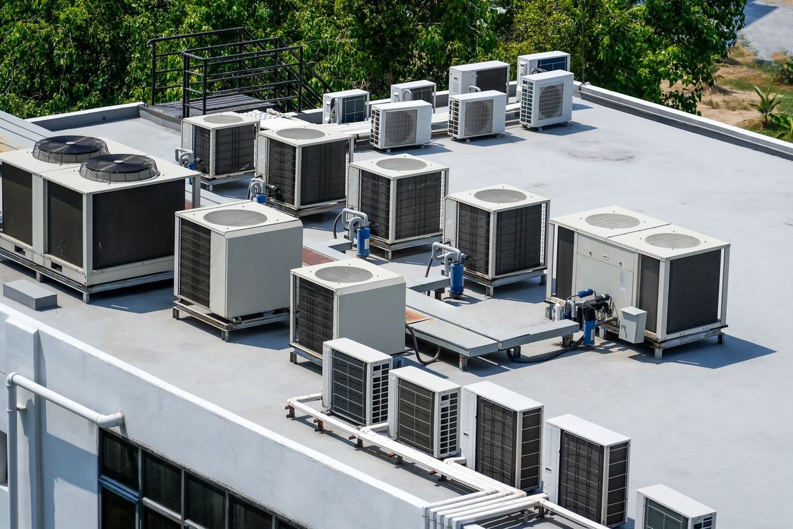 There are a lot of air conditioners on the roof of a building.