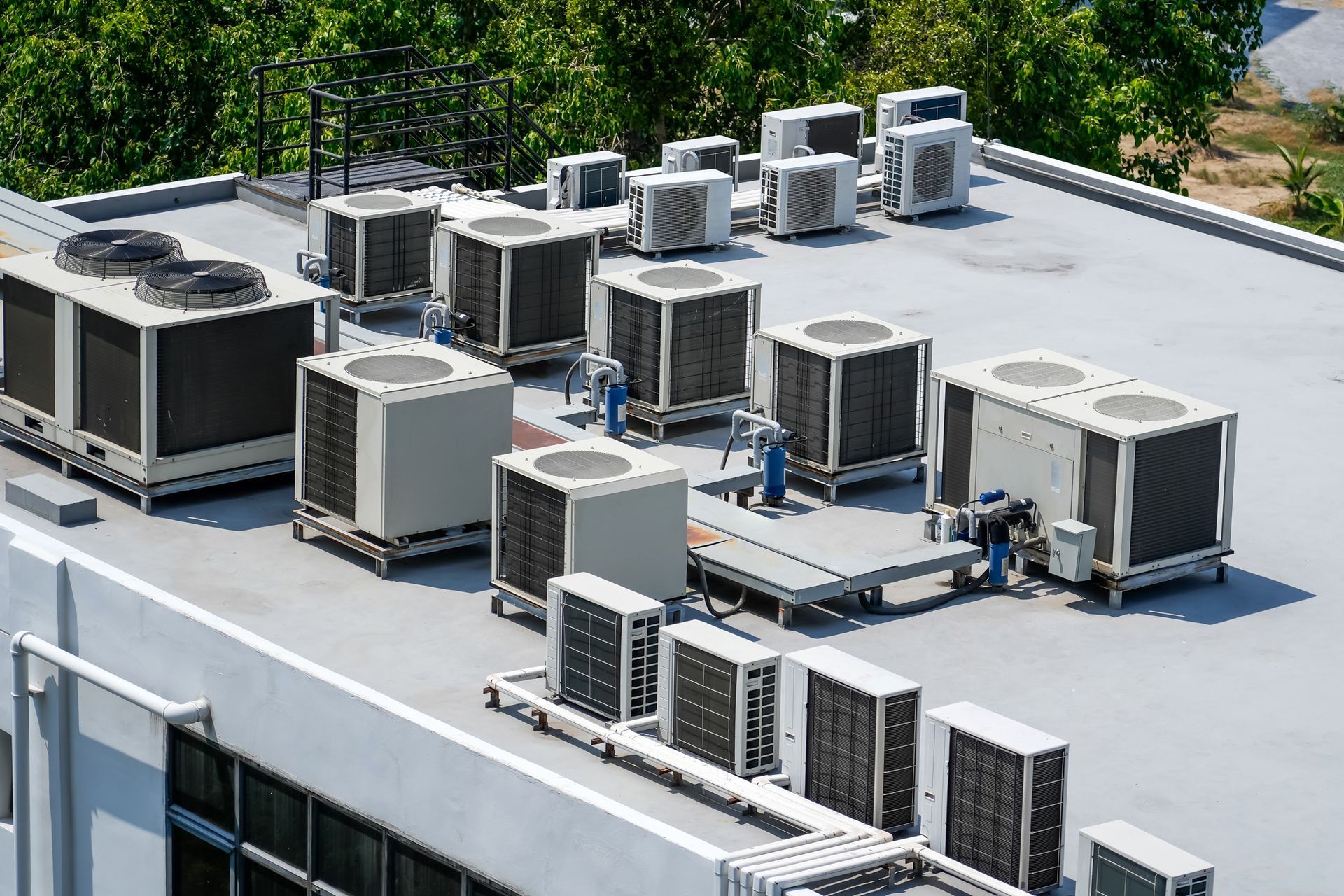 There are a lot of air conditioners on the roof of a building.