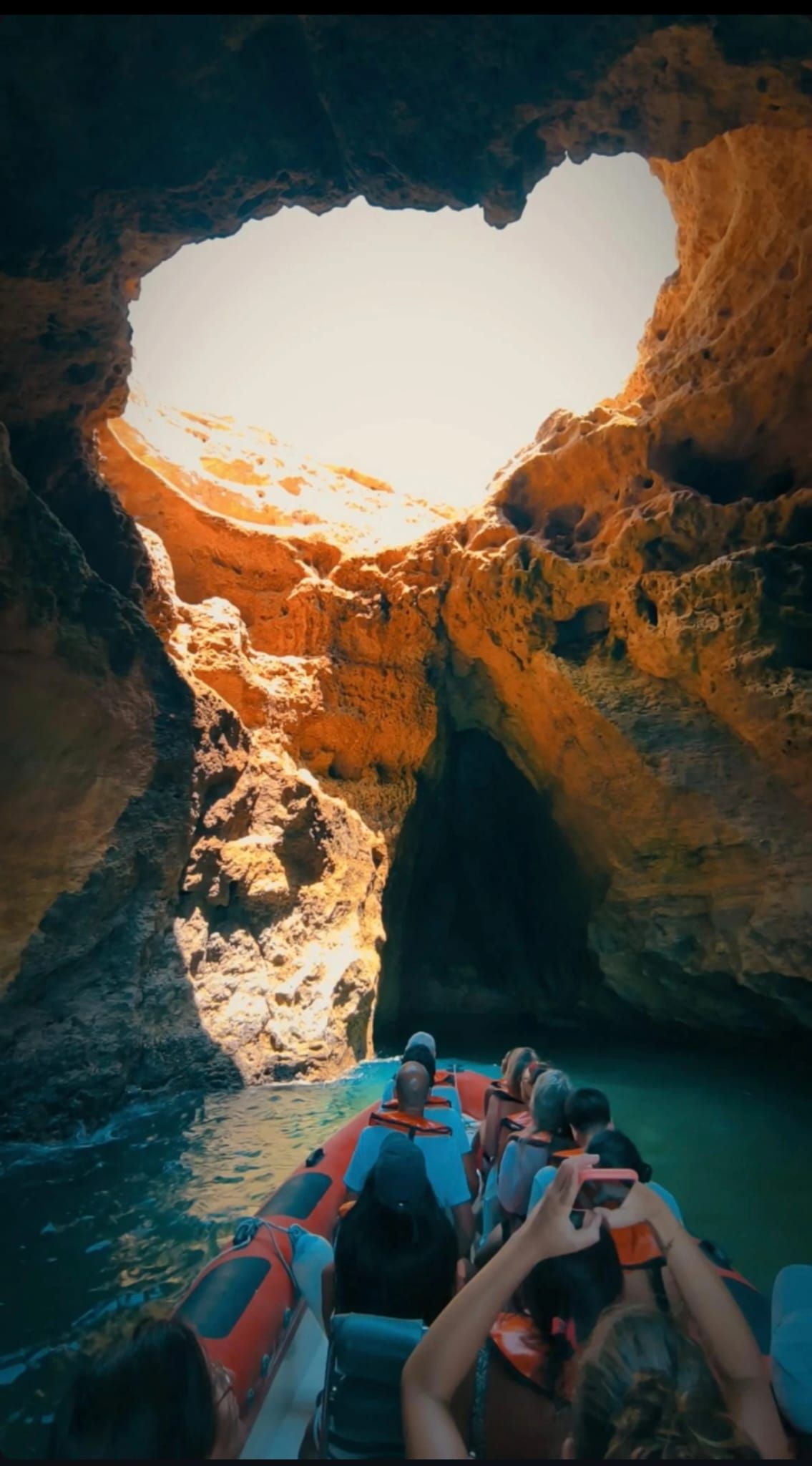 Barco entrando en la cueva de Benagil con luz del sol entrando por el techo – Excursión exclusiva en barco desde Portimão.