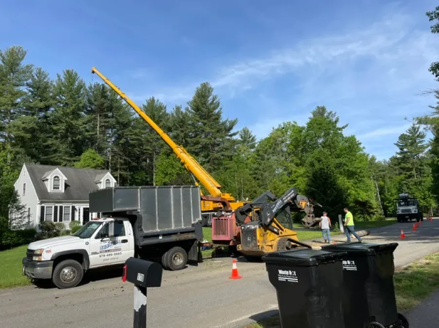 A dump truck with a crane on top of it is parked in front of a house.