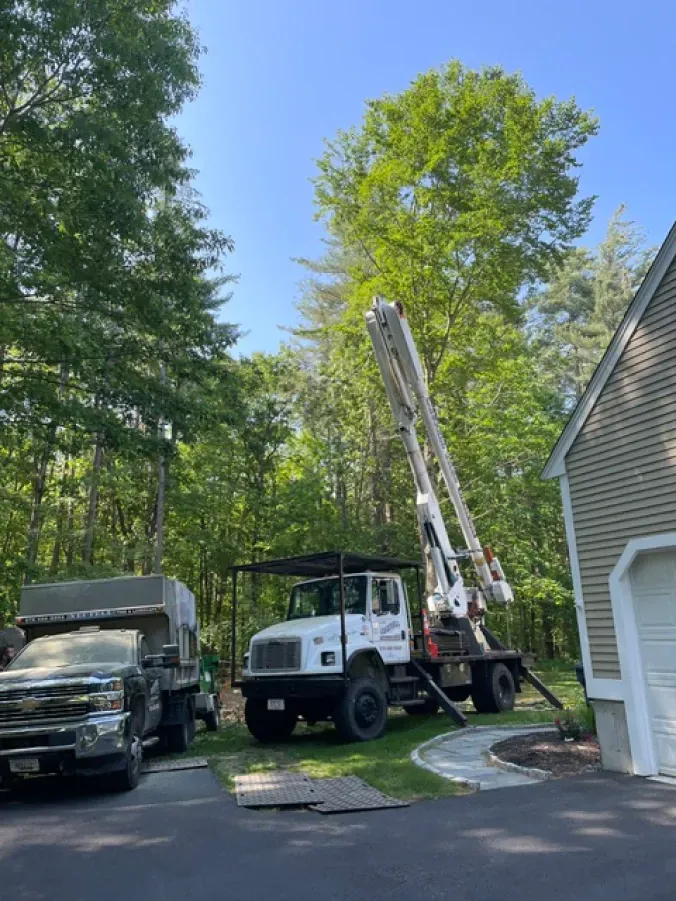 A truck with a crane on top of it is parked in front of a house.
