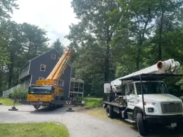 A truck with a crane on top of it is parked in front of a house.
