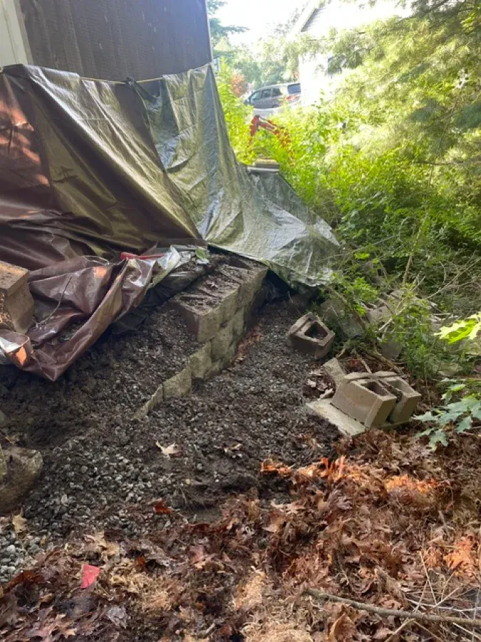 A tarp is covering a pile of concrete blocks in a yard.