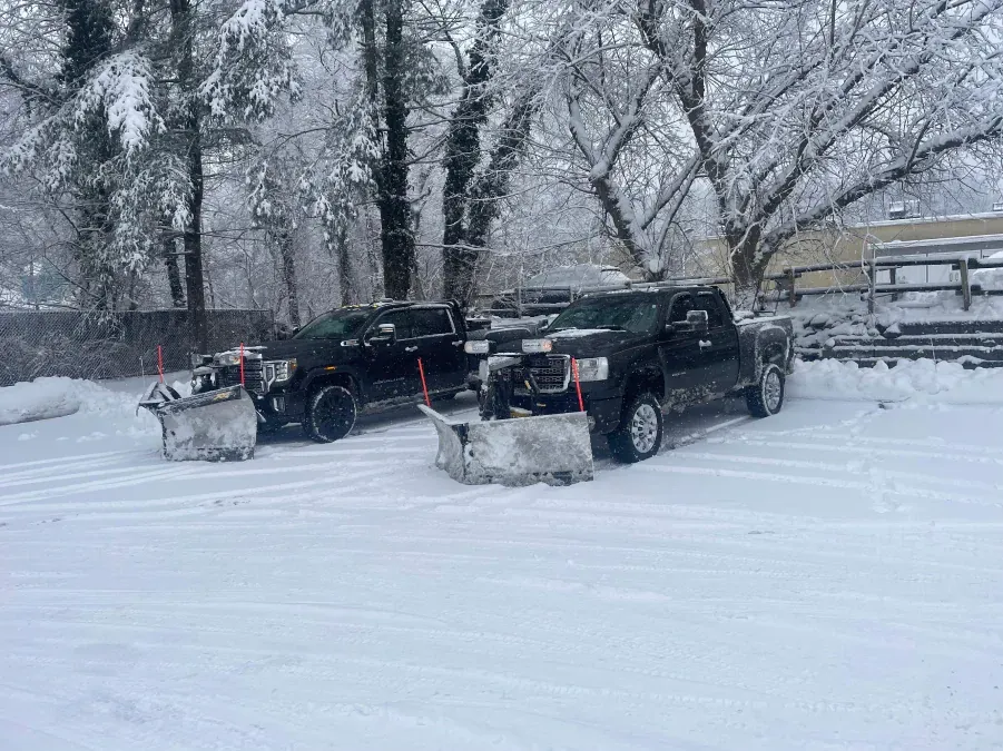 Two snow plows are parked next to each other in the snow.