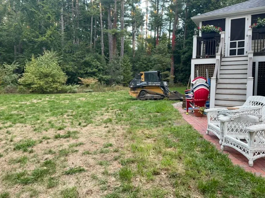 A backyard with a house and a bulldozer in the background.