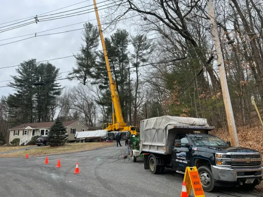 A dump truck is parked on the side of the road next to a crane.