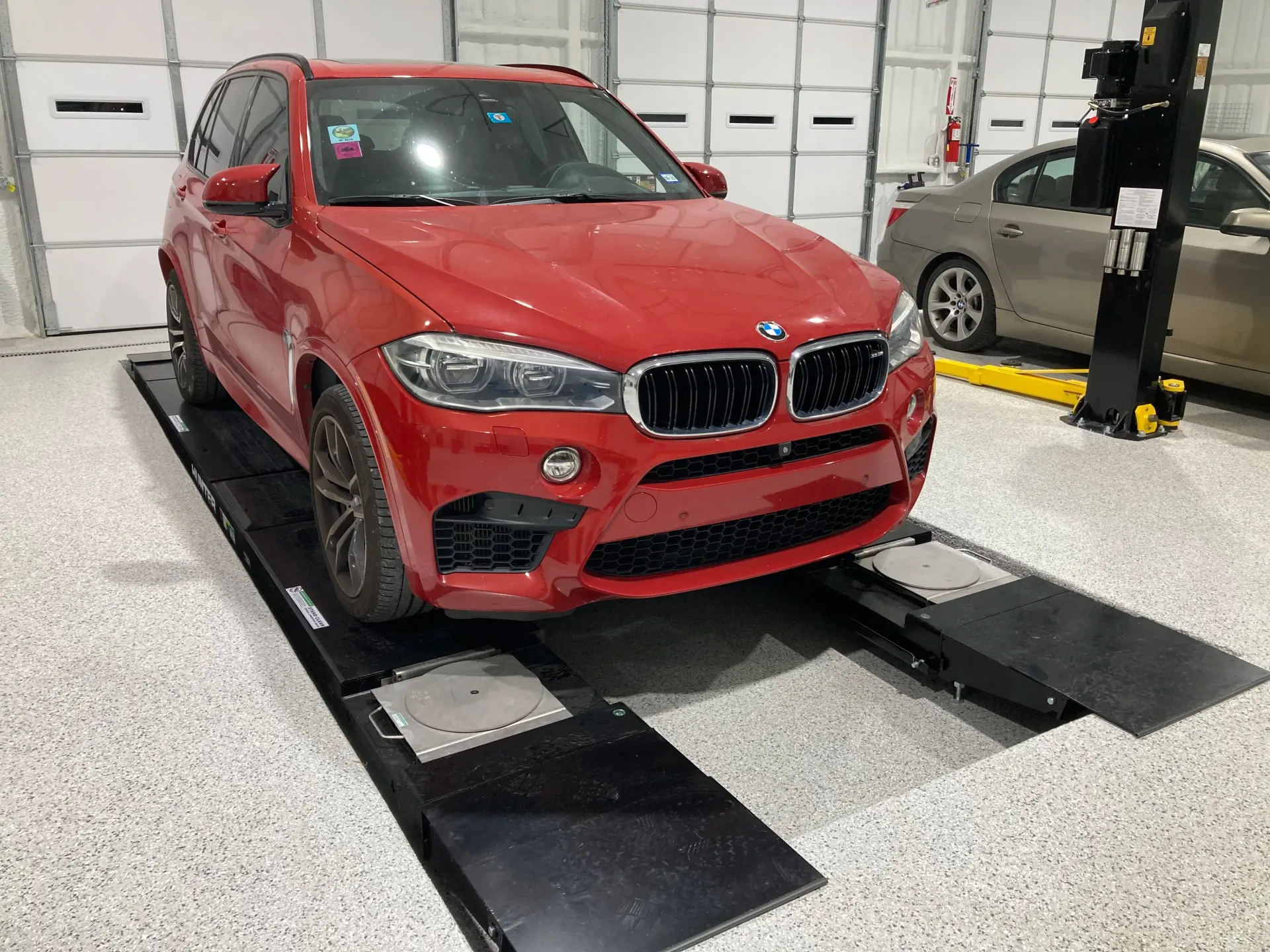 Red BMW SUV on a Black Alignment Lift | Dillon Auto Repair