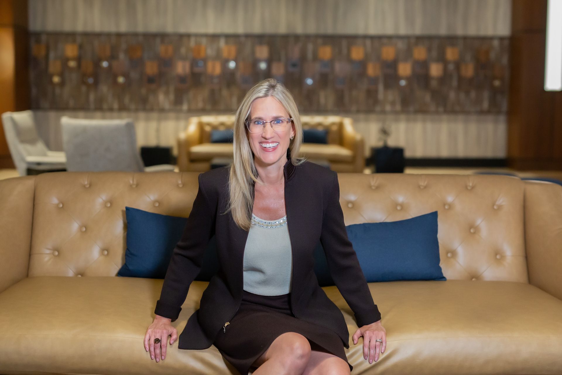 A woman in a suit is sitting on a couch.