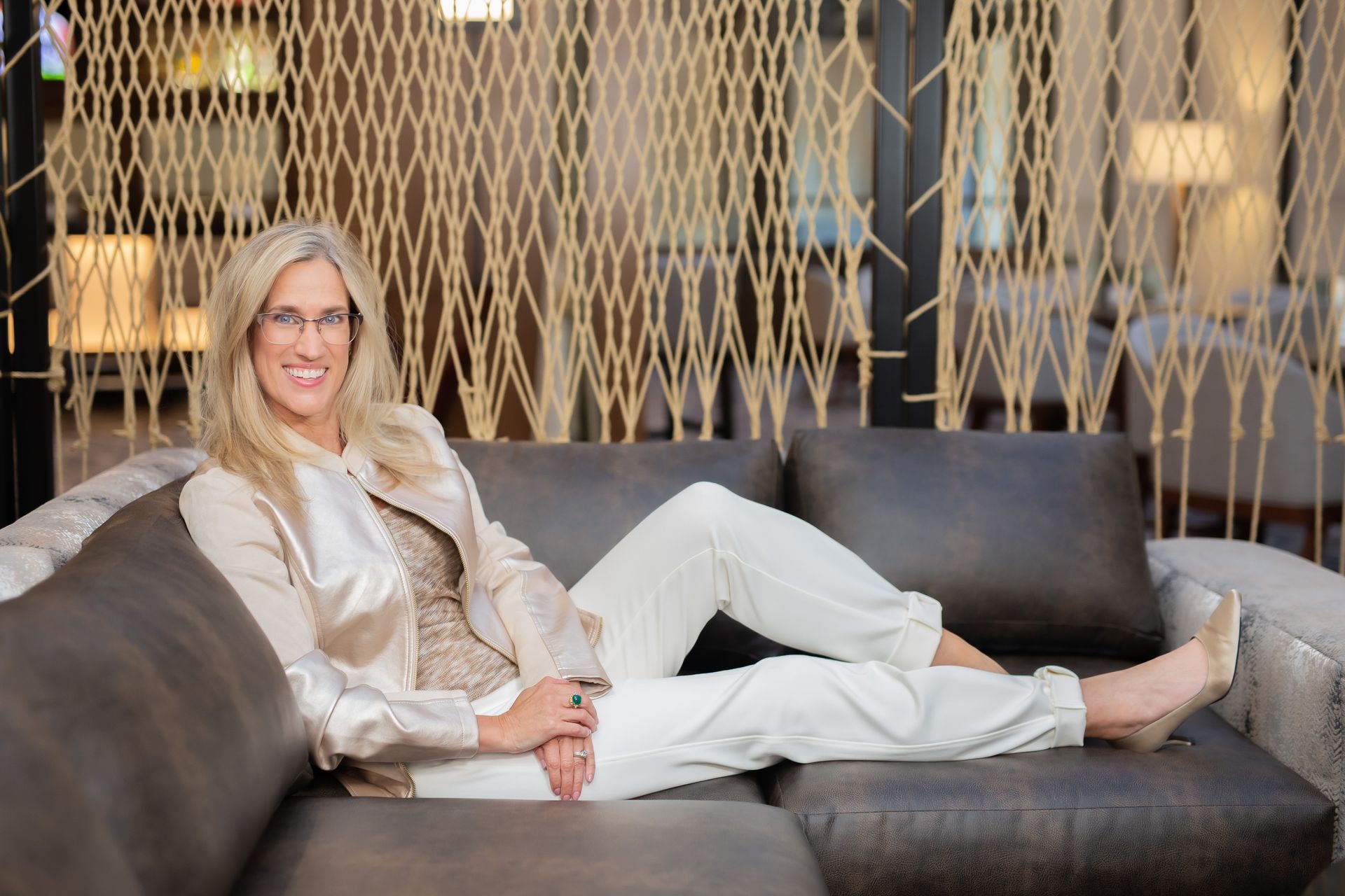 A woman is sitting on a couch with her legs crossed and smiling.