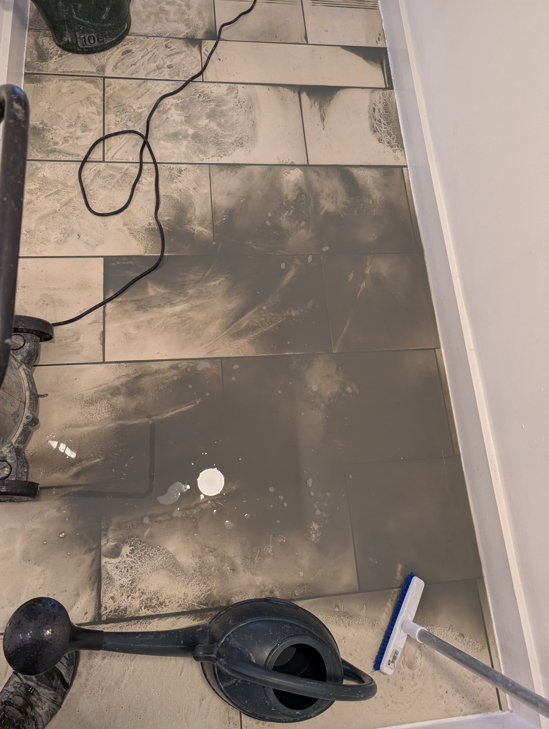 Close-up of dirty rinse water extracted during deep cleaning of lobby tiles at No.1 Deansgate Manchester, showing removal of built-up grime and years of foot traffic from porcelain and stone flooring.