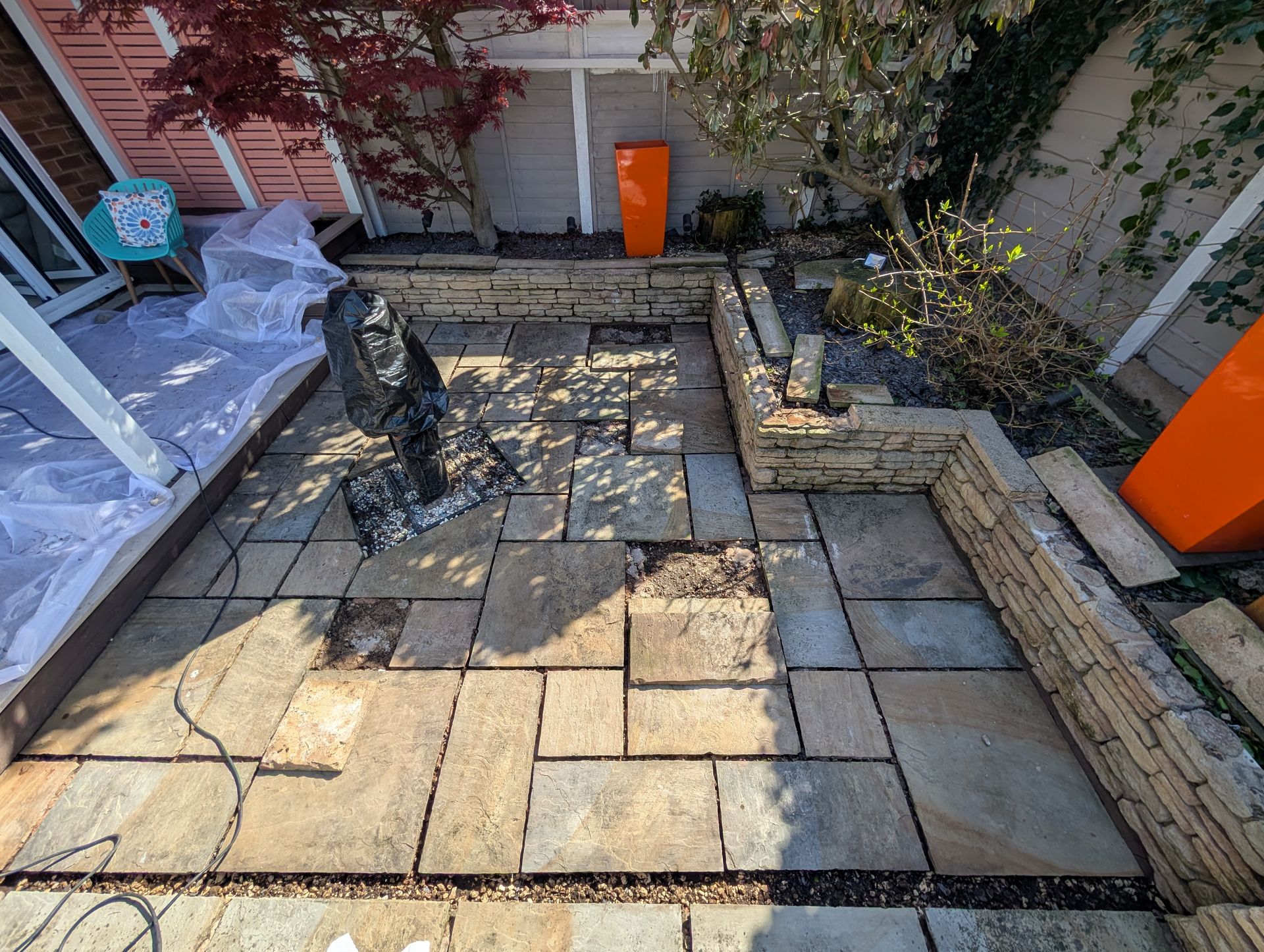 Several lifted patio tiles carefully removed and laid to the side, exposing underlying mortar bed in preparation for re-fixing and restoration.