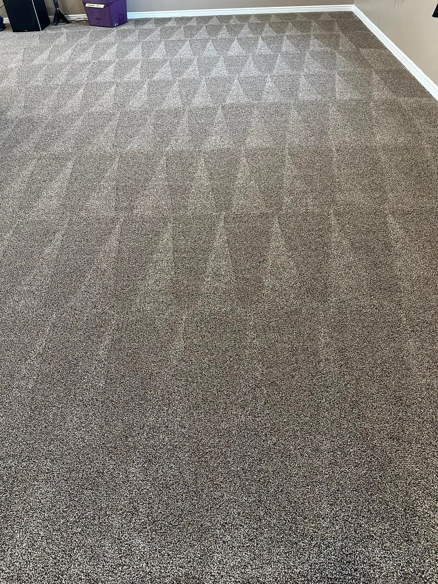 A large carpeted floor in a room with a purple bag on it.