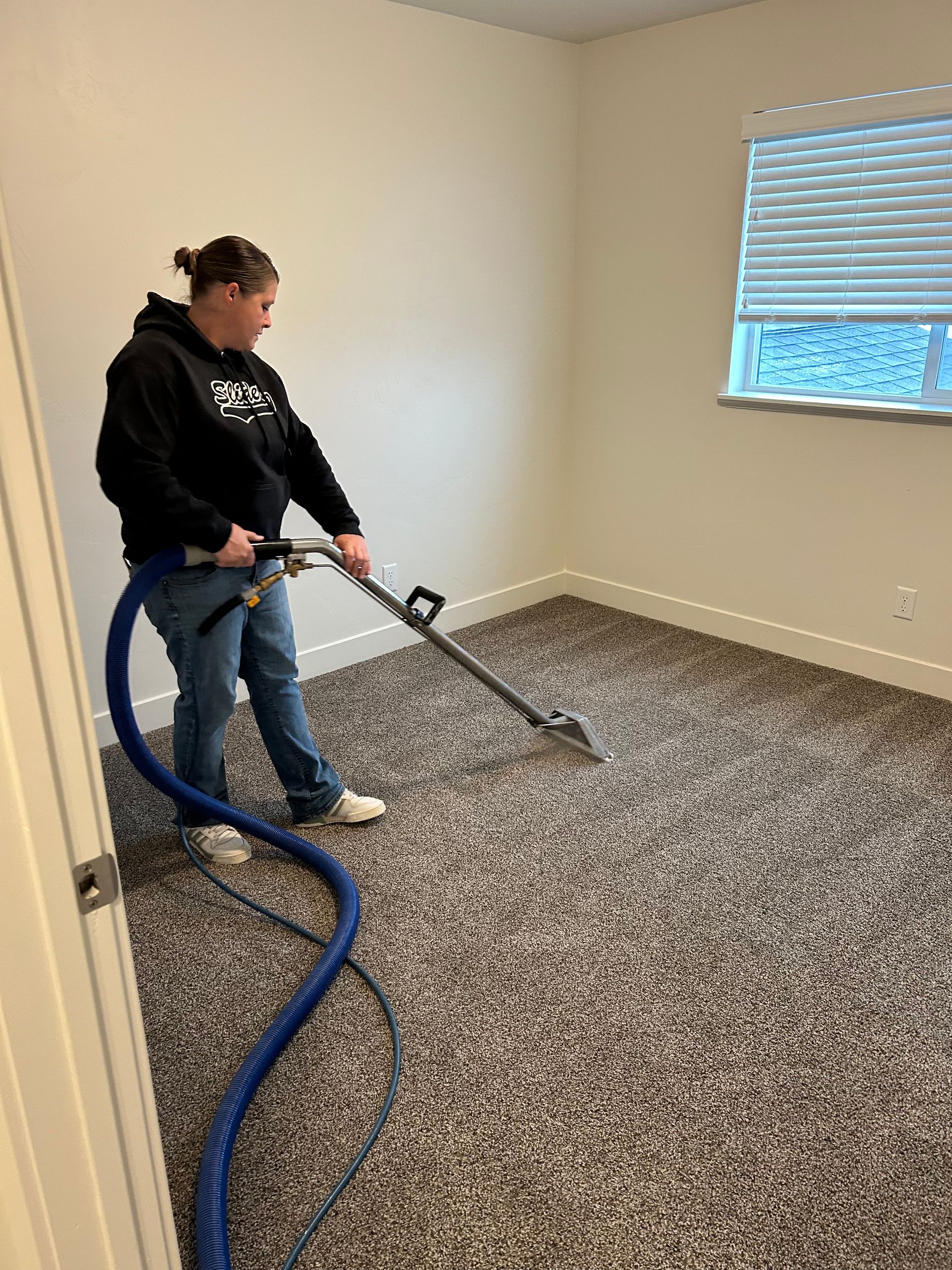 A woman is using a vacuum cleaner to clean a carpet in a room.