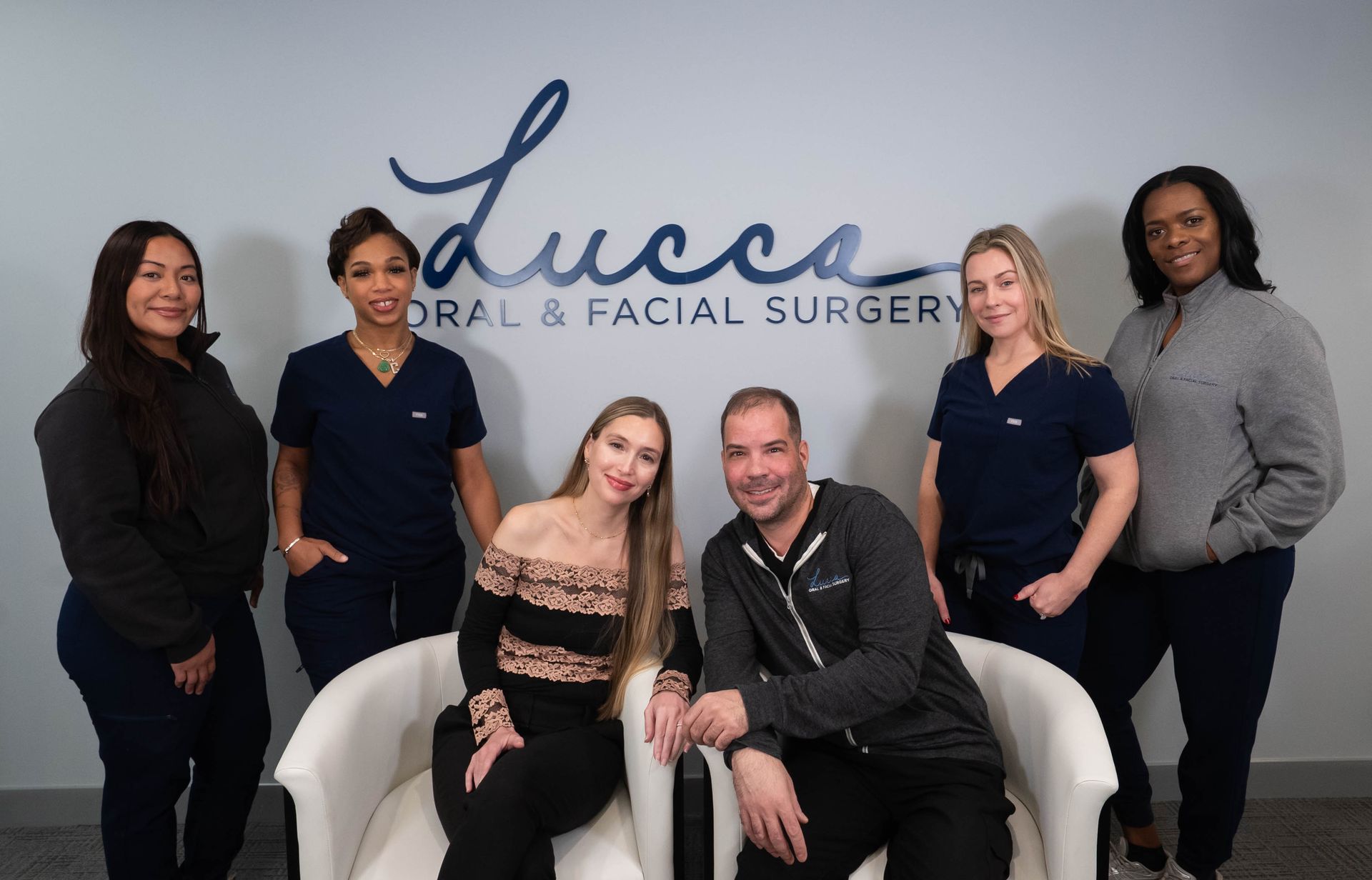 Group of six people posing in front of a sign that reads Lucca Oral & Facial Surgery