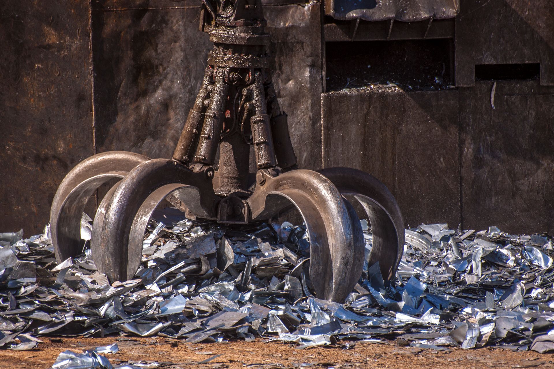Un grande artiglio di metallo sta infilando la mano in un mucchio di rottami metallici