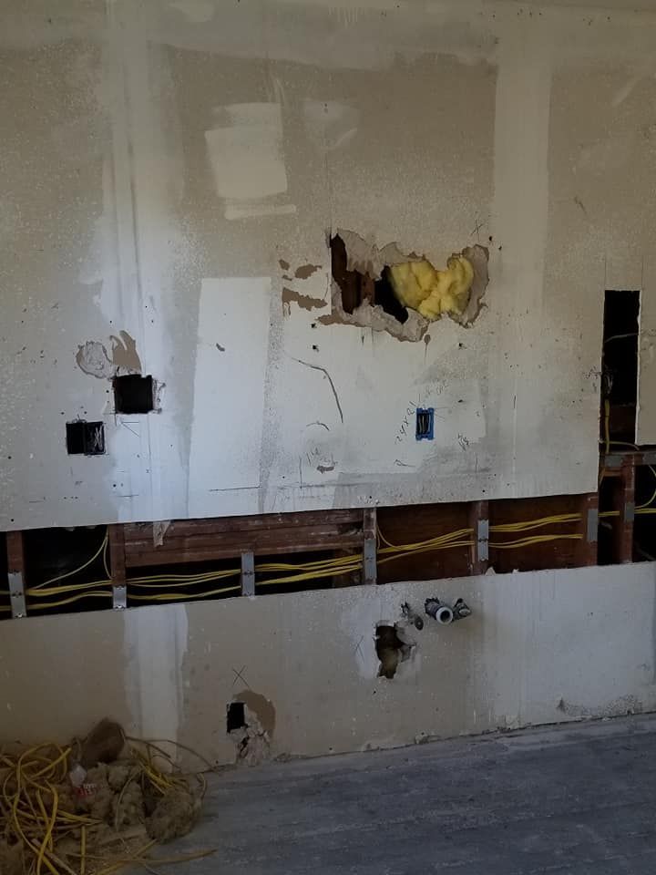 A wall with holes in it and a bunch of wires coming out of it