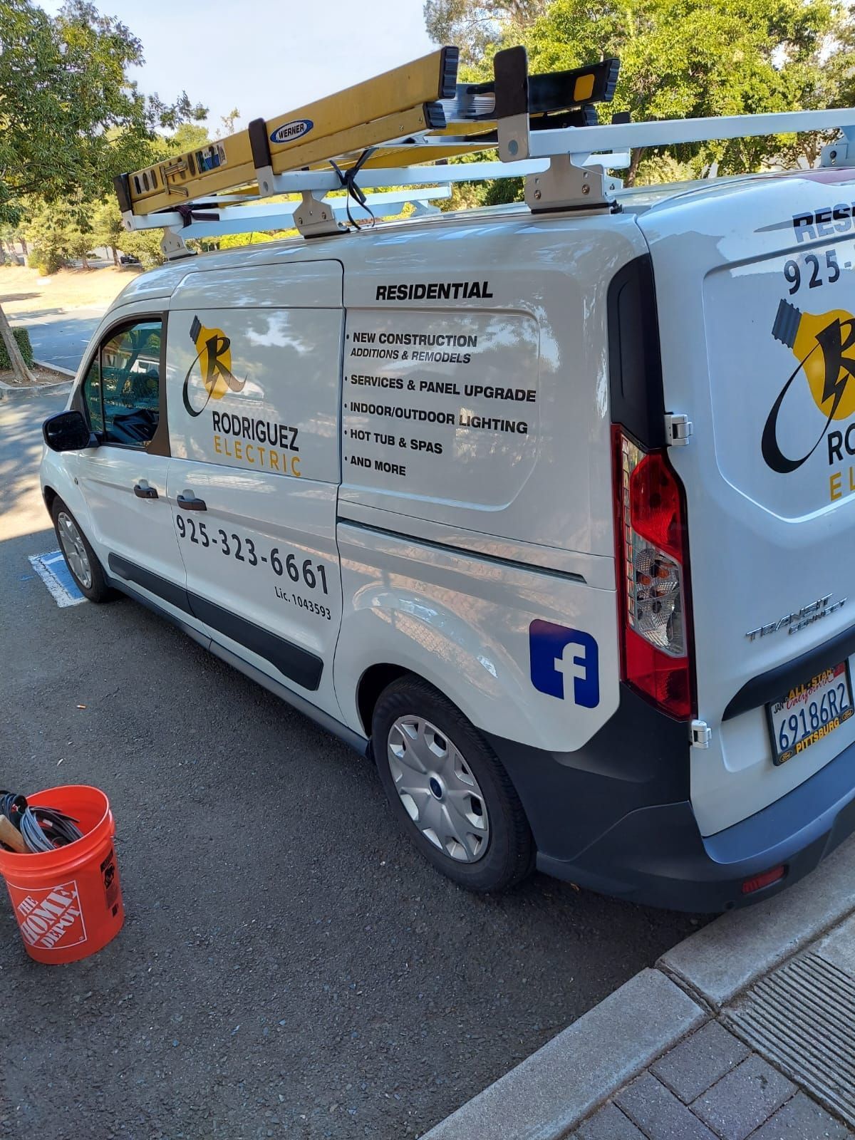 A white van with a ladder on top of it is parked on the side of the road.