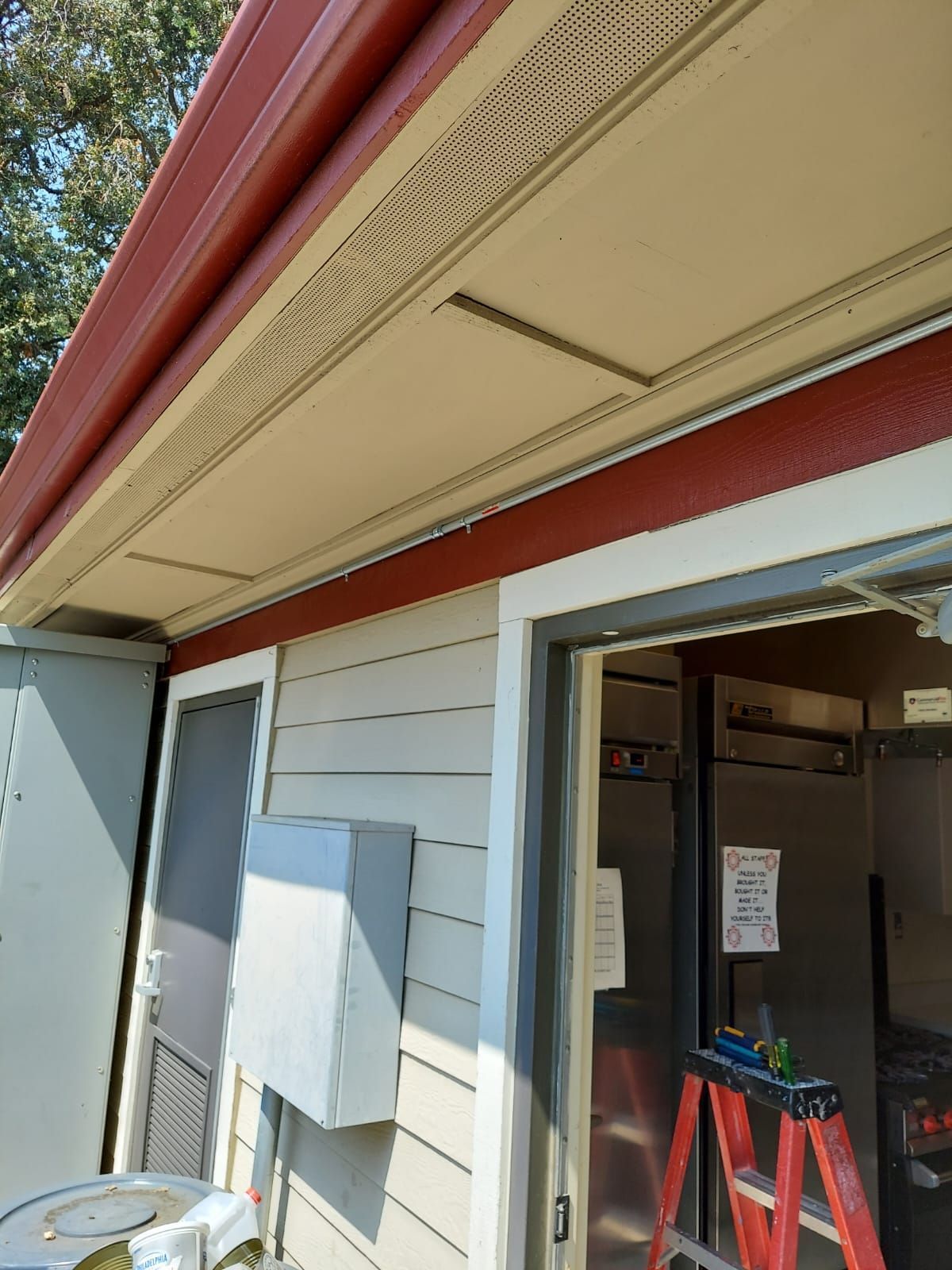 A red ladder is sitting on the side of a house.