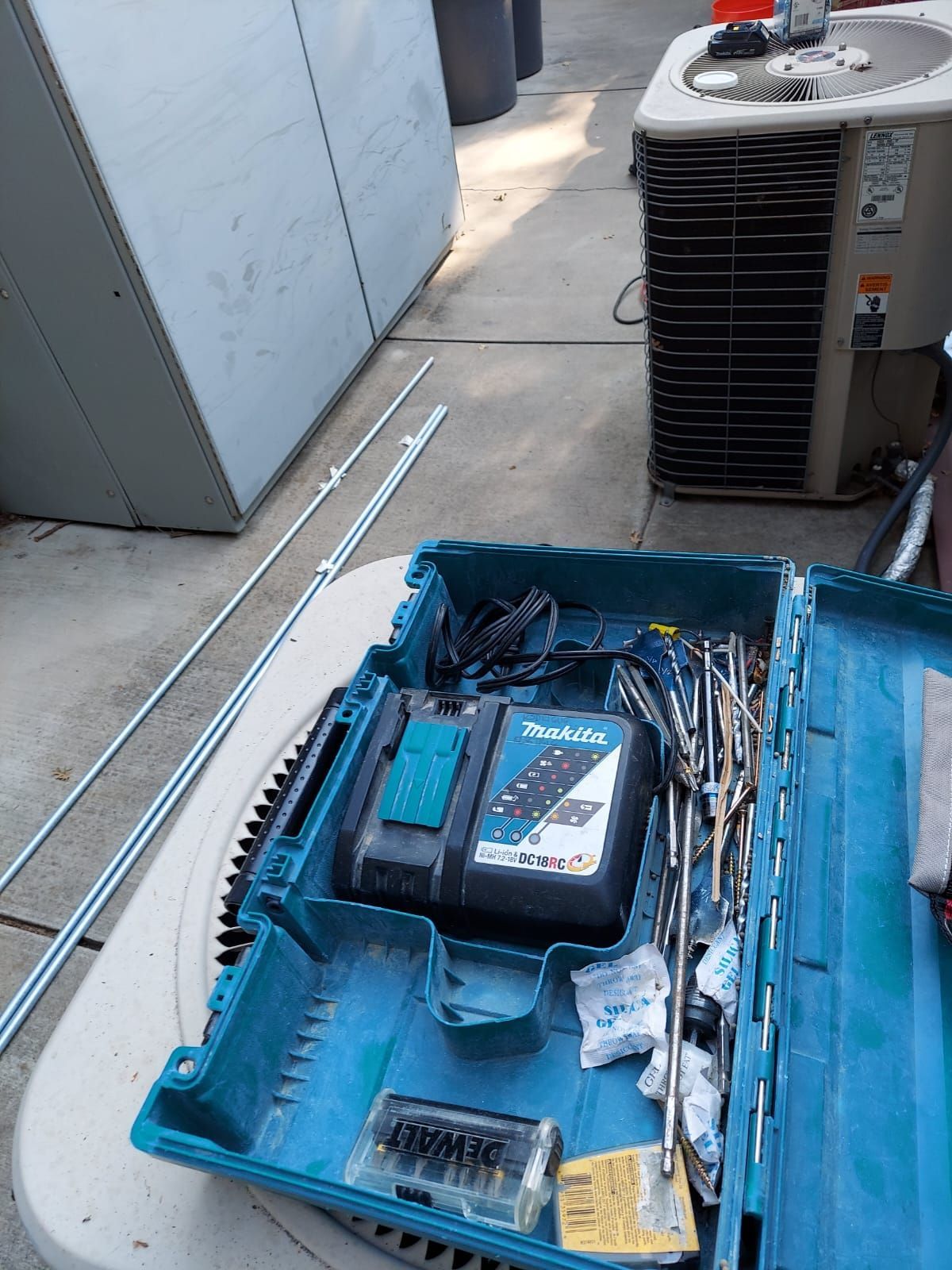 A toolbox filled with tools and a charger is sitting on a table.