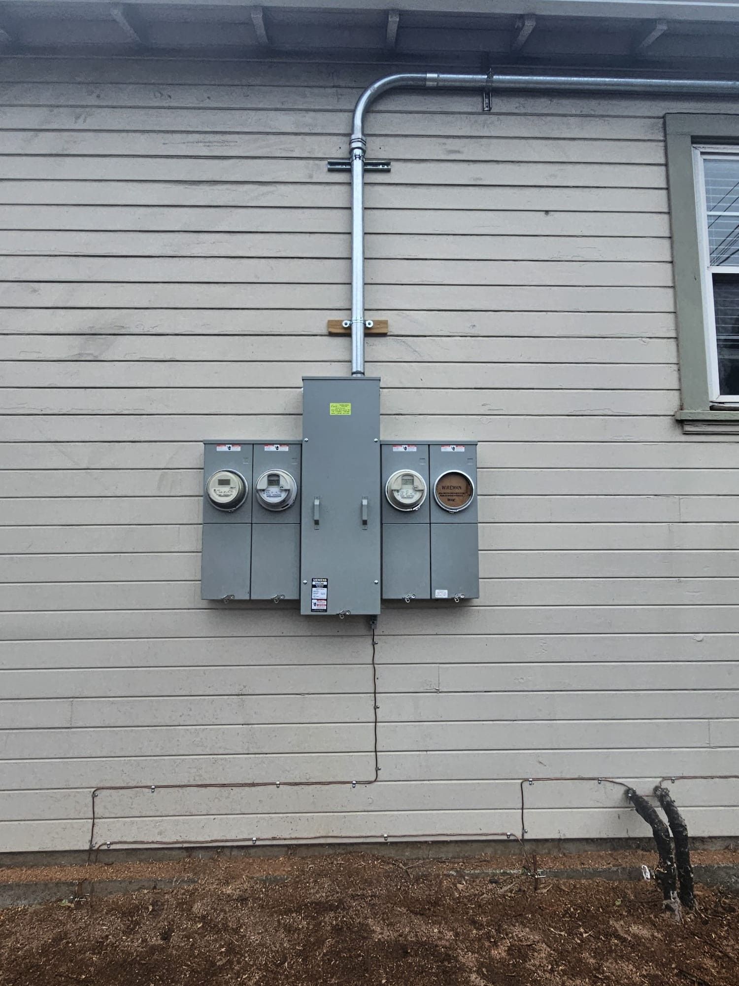 There is a electrical box on the side of a house.