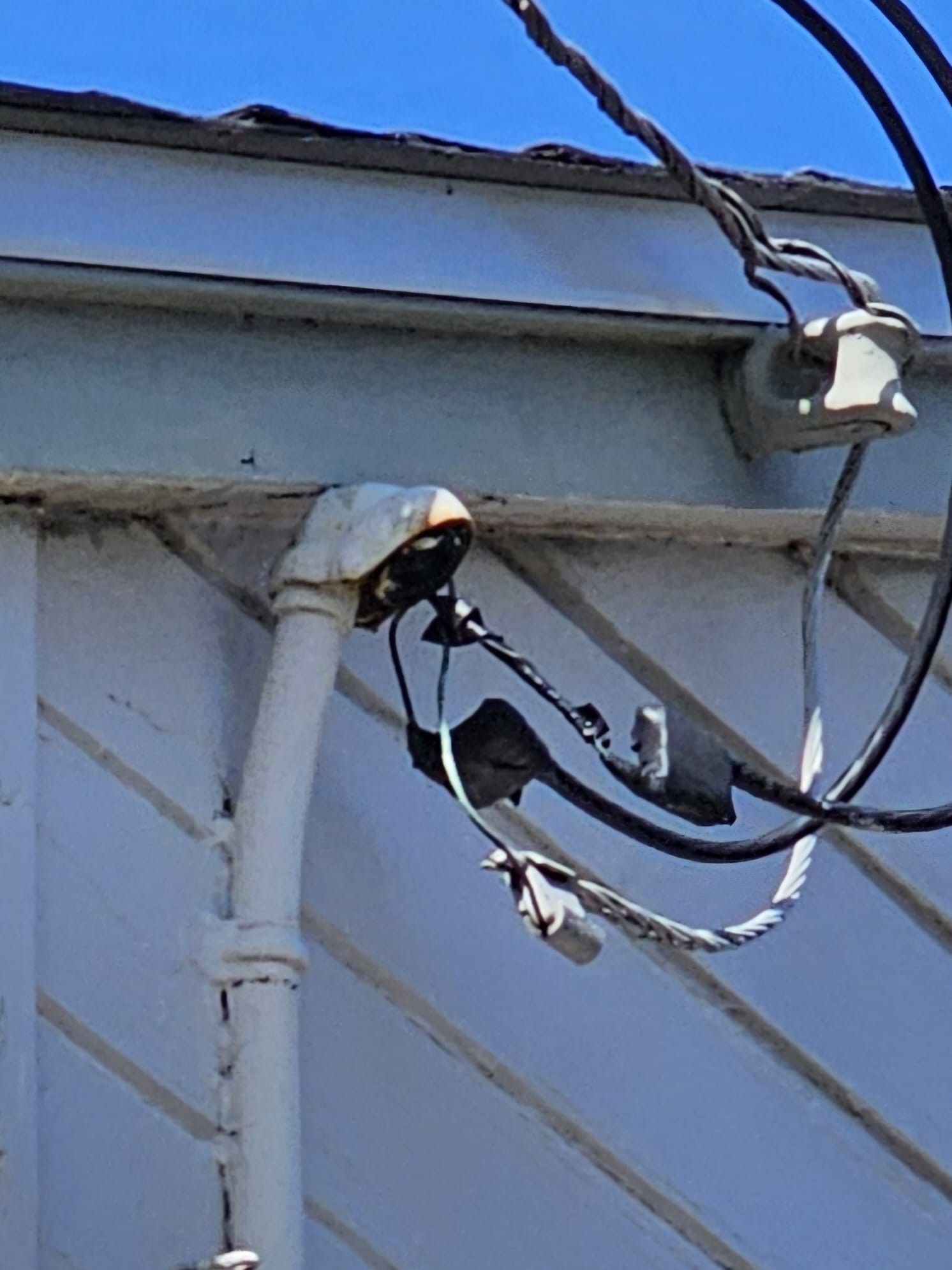 A bunch of wires are hanging from the side of a building