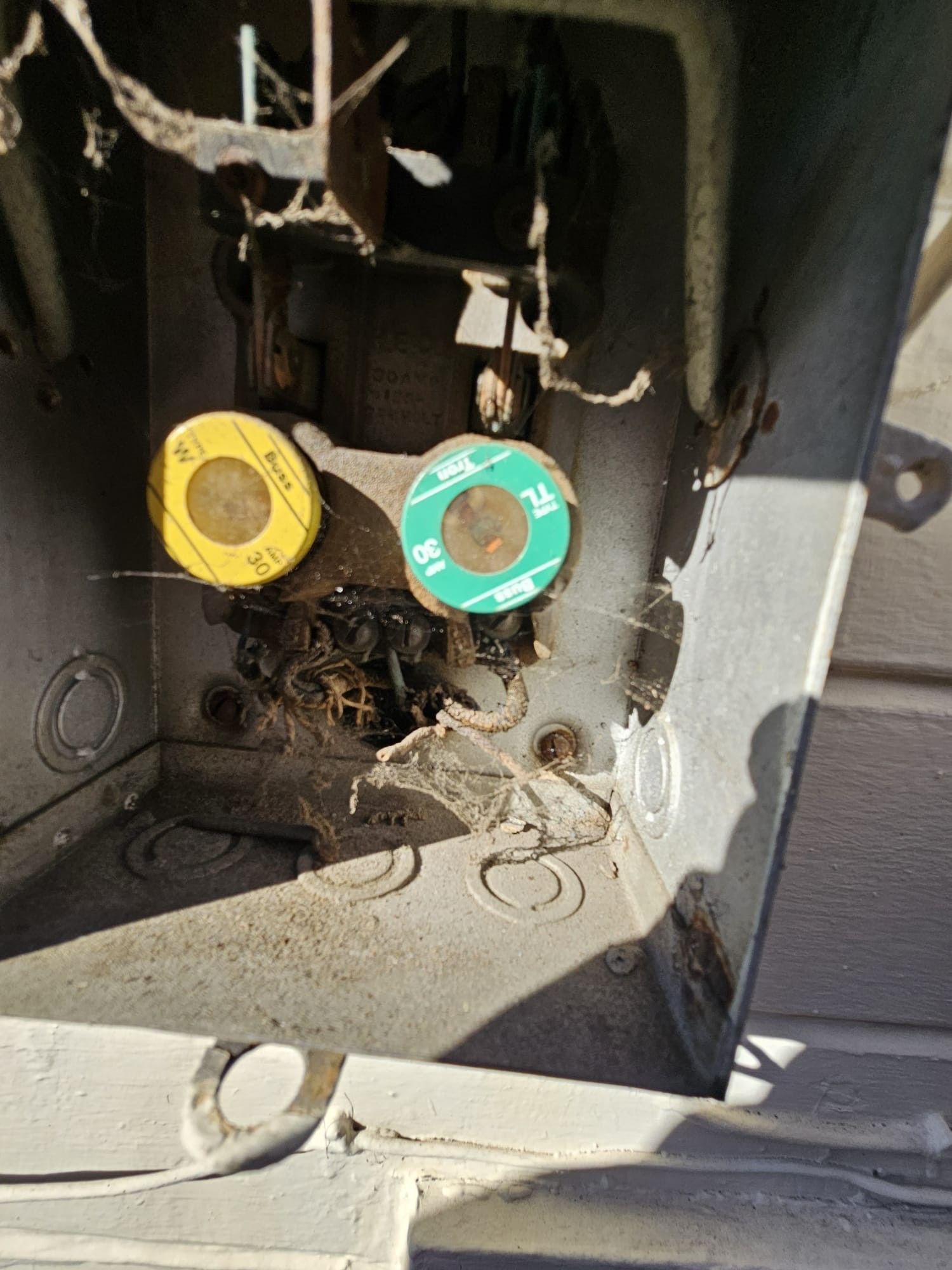 A close up of a broken electrical box with a yellow and green sticker on it.