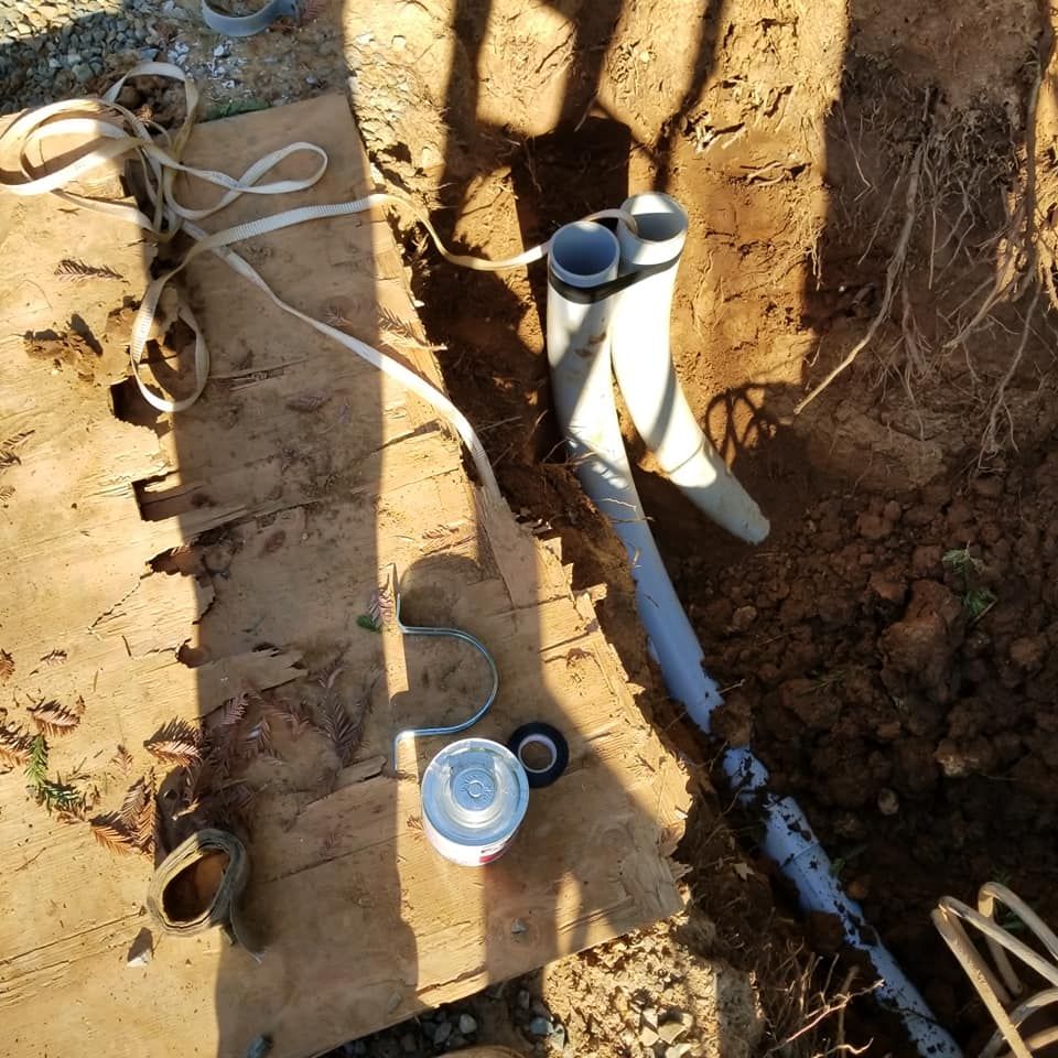 A bunch of pipes are laying in the dirt