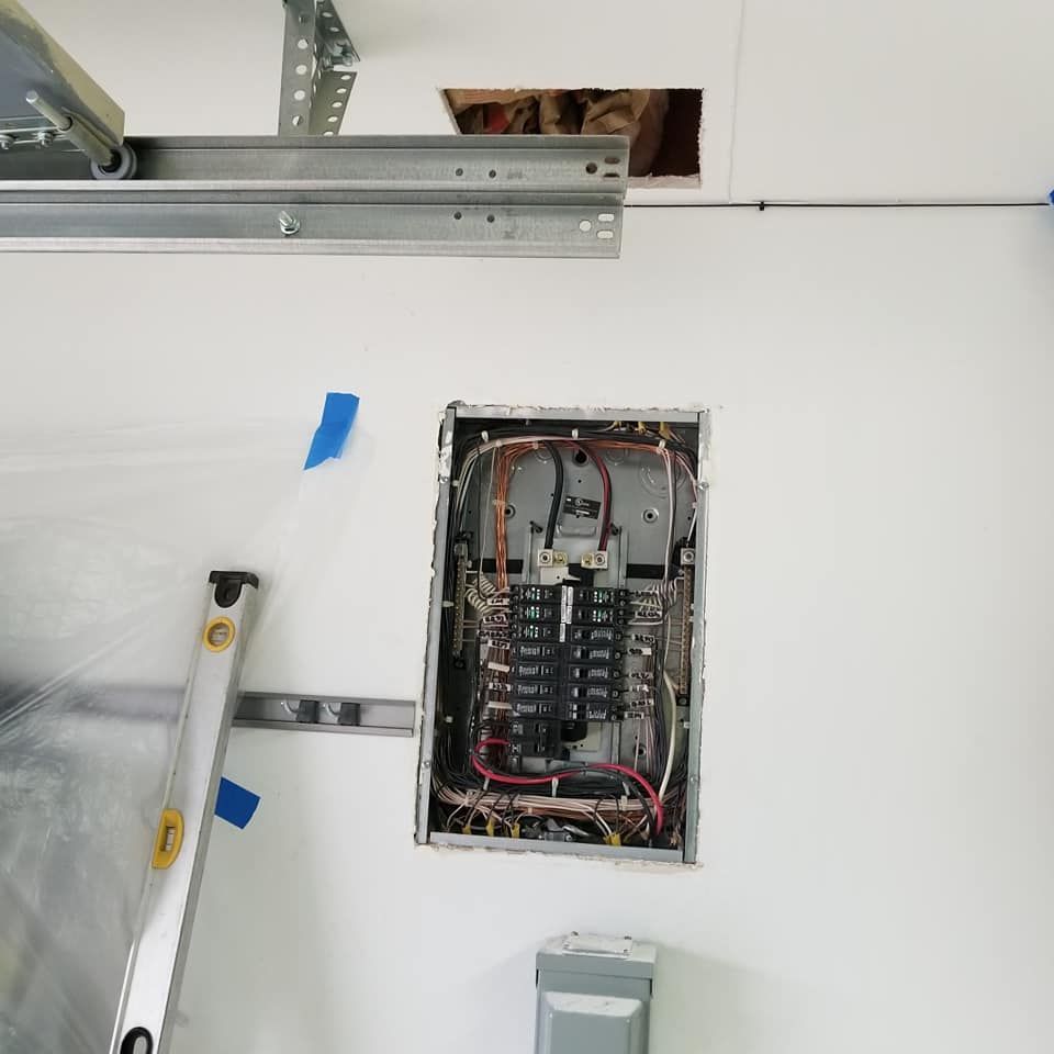 A ladder is sitting next to a electrical box on a white wall.
