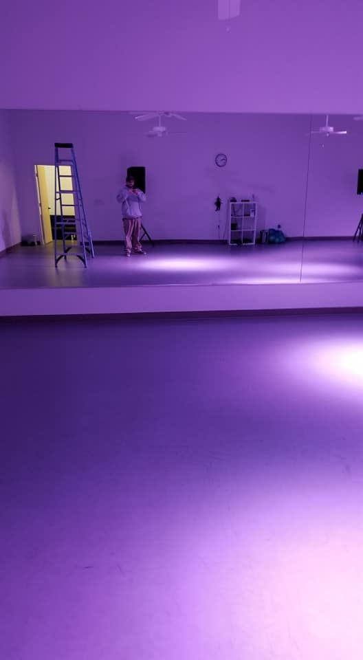 A person is standing in front of a large mirror in a purple room.