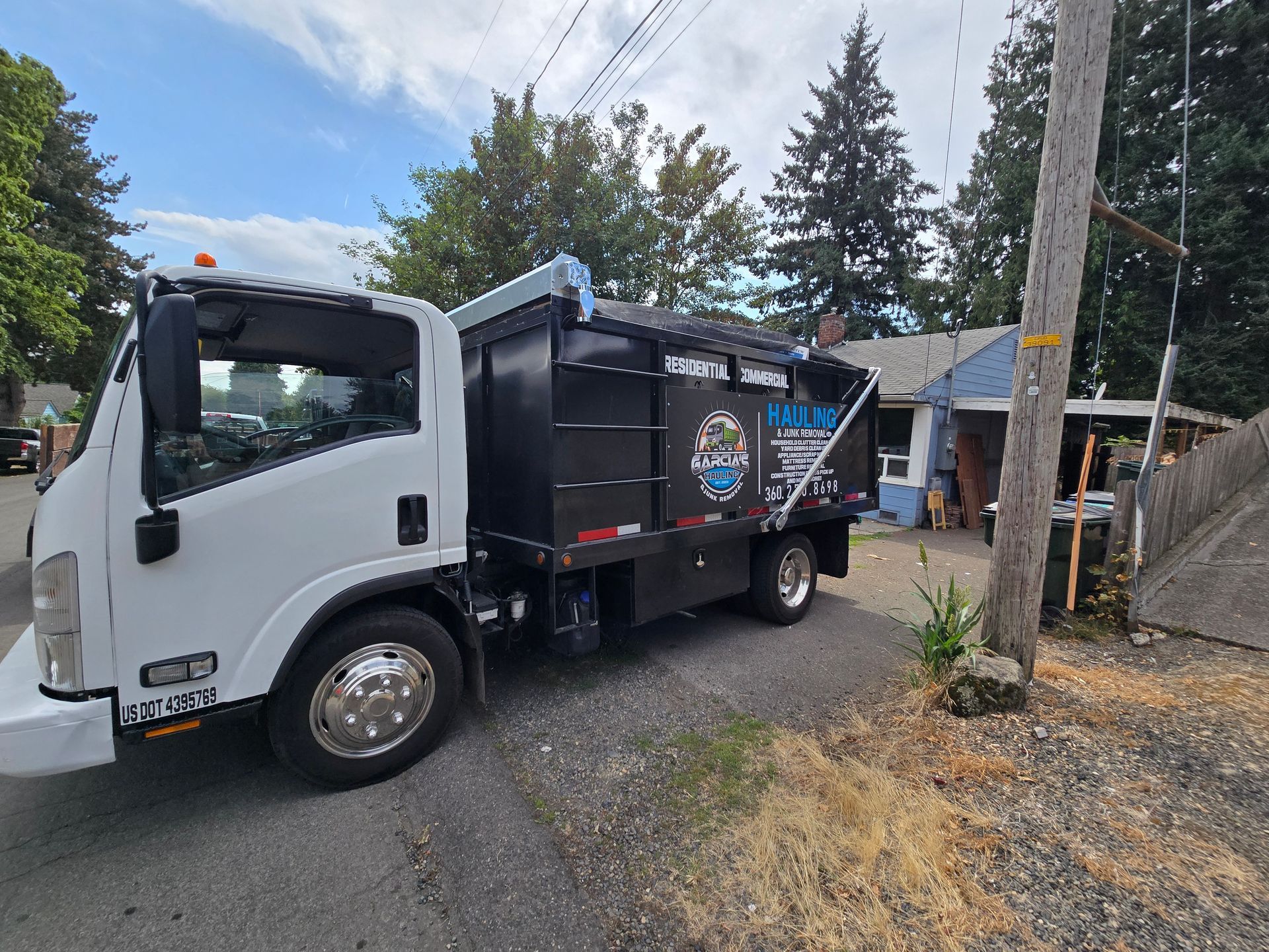 A truck bed filled with colorful cushions driving down a road lined with houses and trees.
