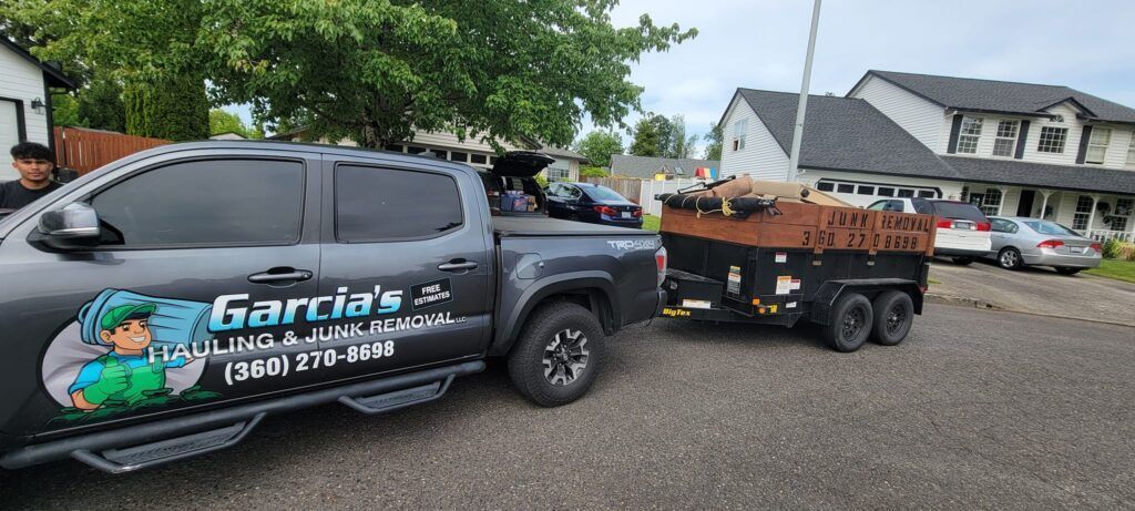 Gray pickup truck with a trailer, parked in a gravel lot. 